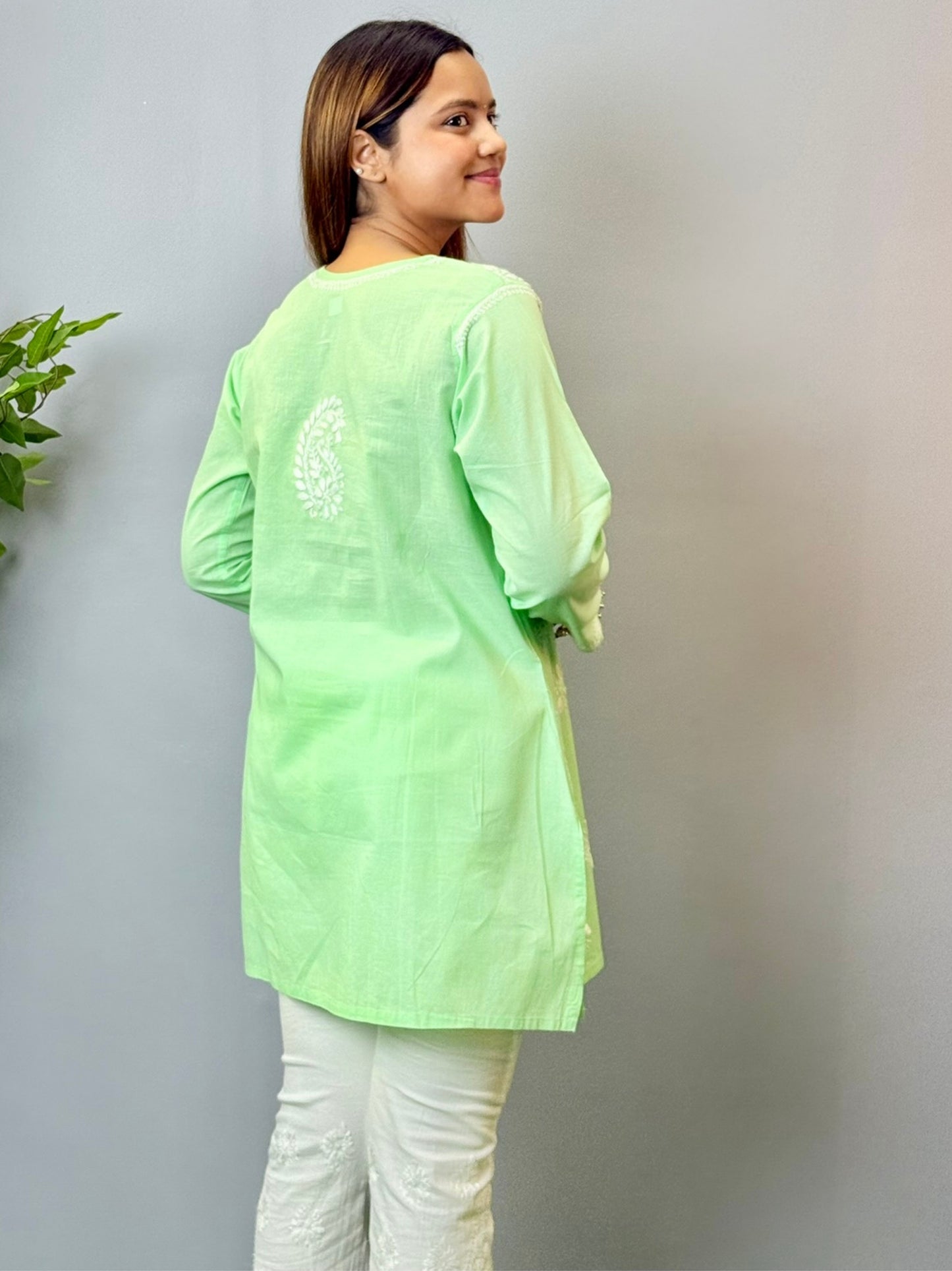 Model wearing a mint green cotton short Lucknowi chikankari kurta with white embroidery, paired with white straight pants.