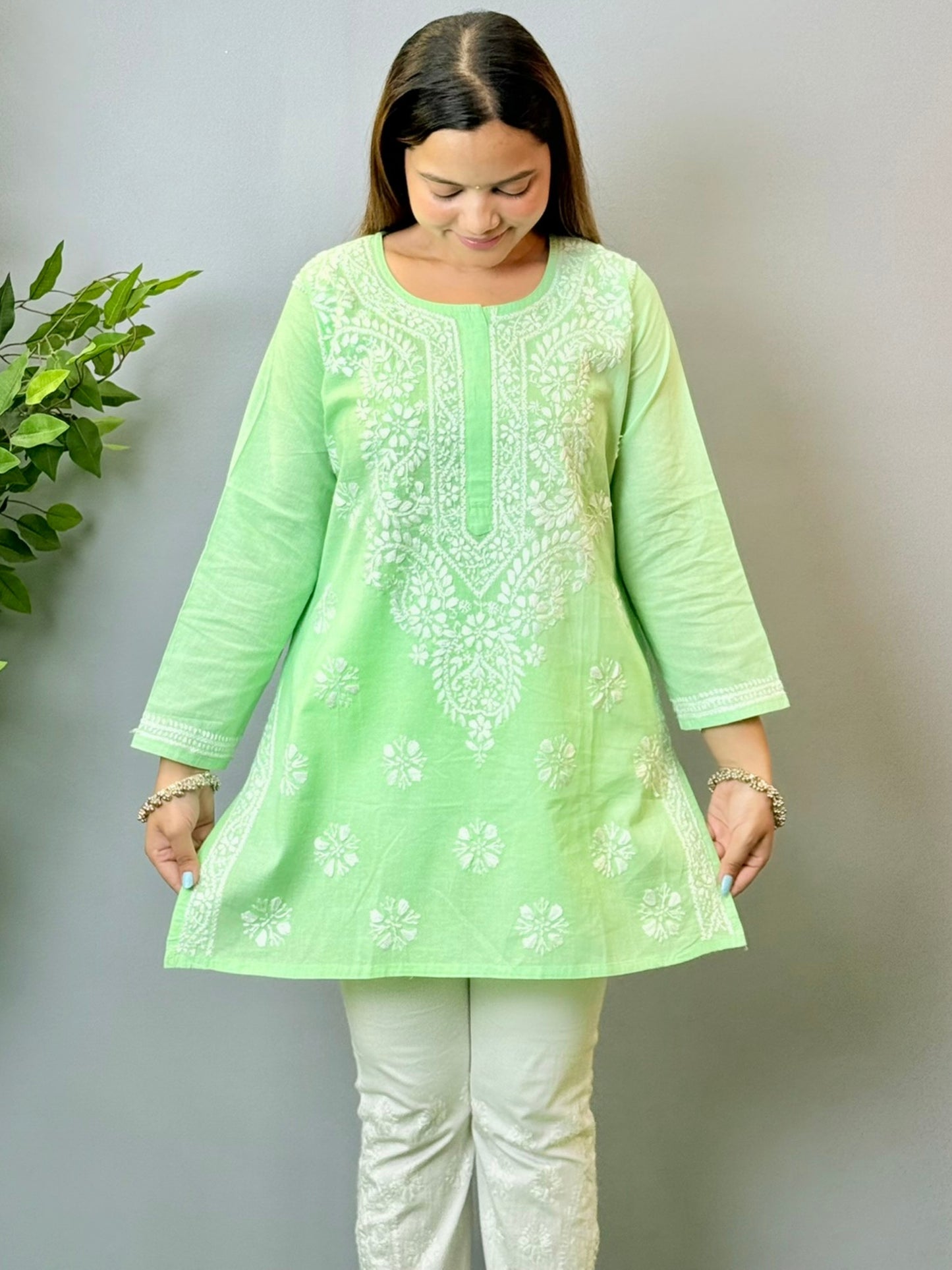 Model wearing a mint green cotton short Lucknowi chikankari kurta with white embroidery, paired with white straight pants.