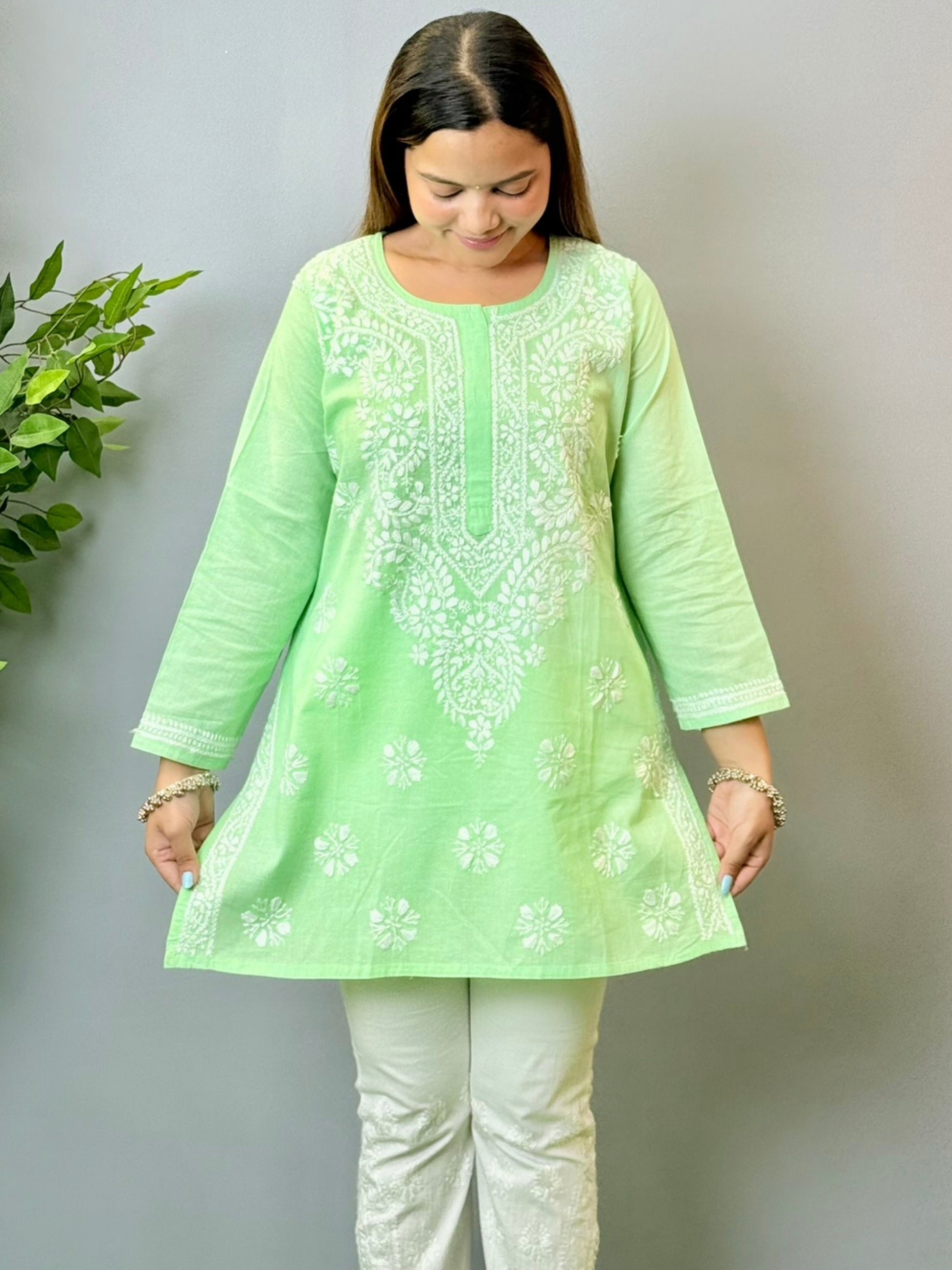 Model wearing a mint green cotton short Lucknowi chikankari kurta with white embroidery, paired with white straight pants.