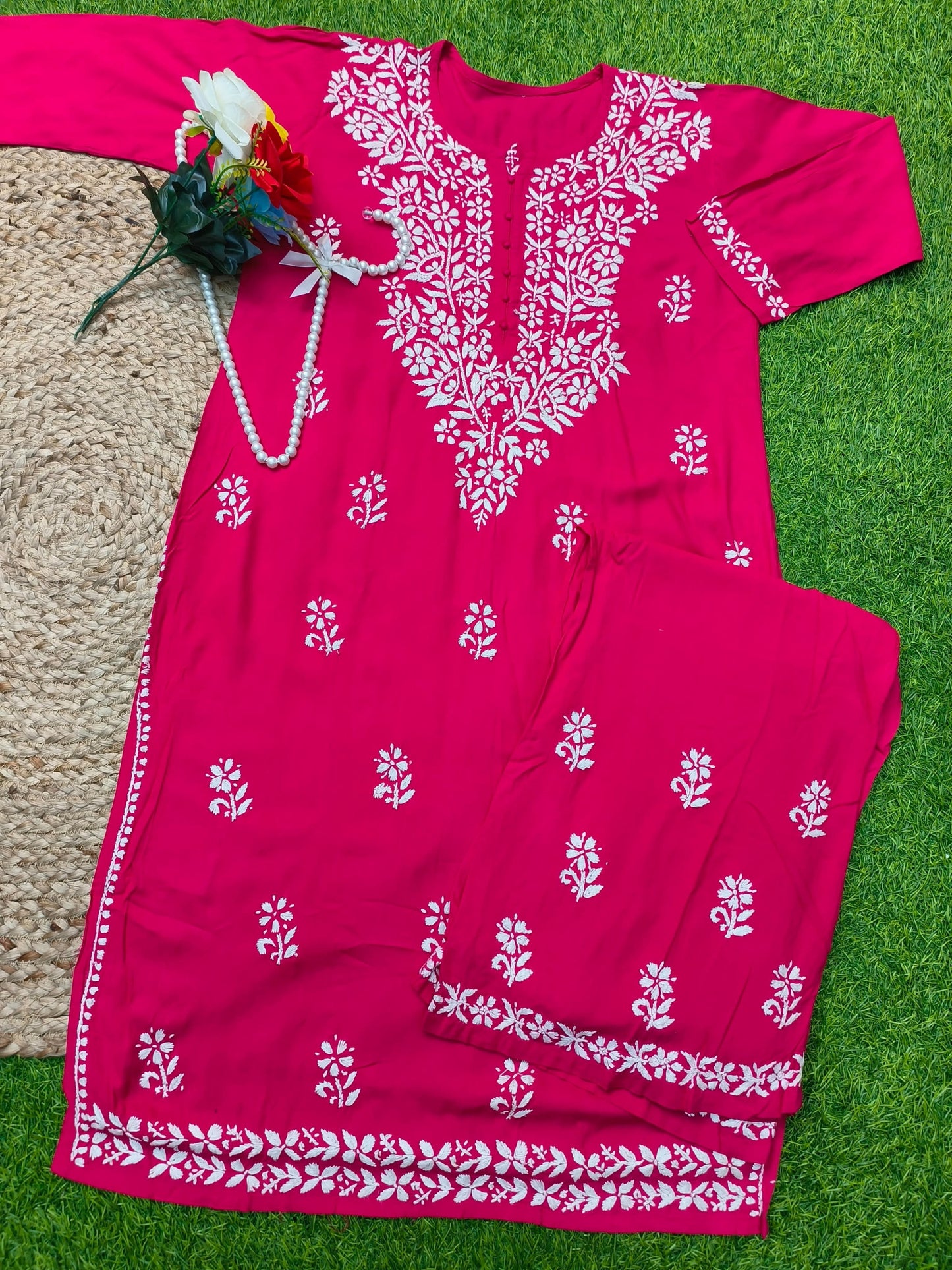 Flat lay of premium rani pink rayon Lucknowi Chikankari kurta and palazzo set with white floral embroidery and detailed borders, by R S CHIKANKARI.