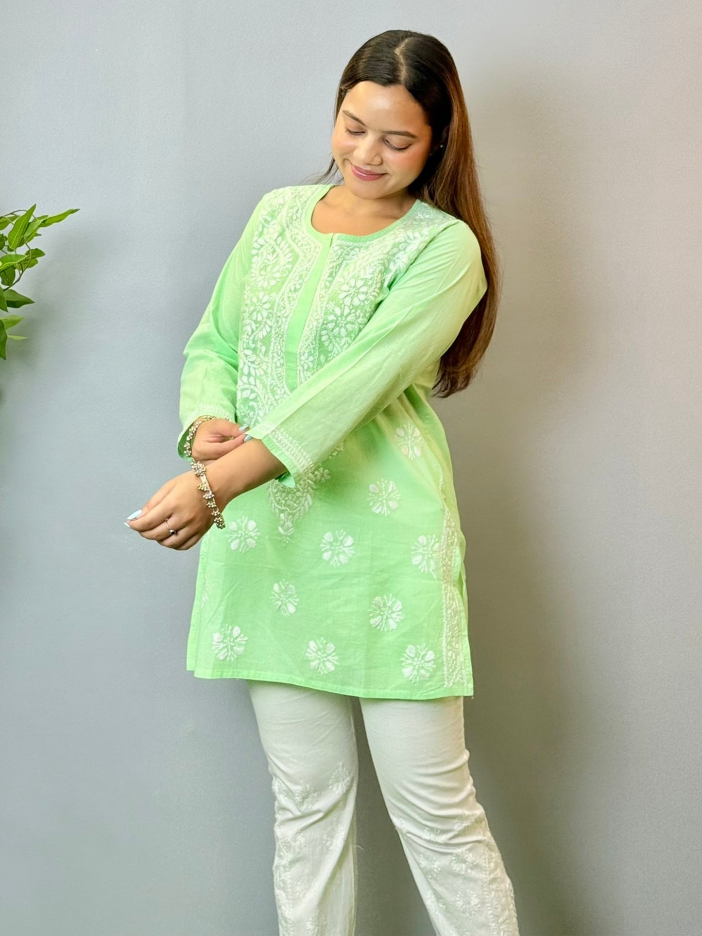 Model wearing a mint green cotton short Lucknowi chikankari kurta with white embroidery, paired with white straight pants.