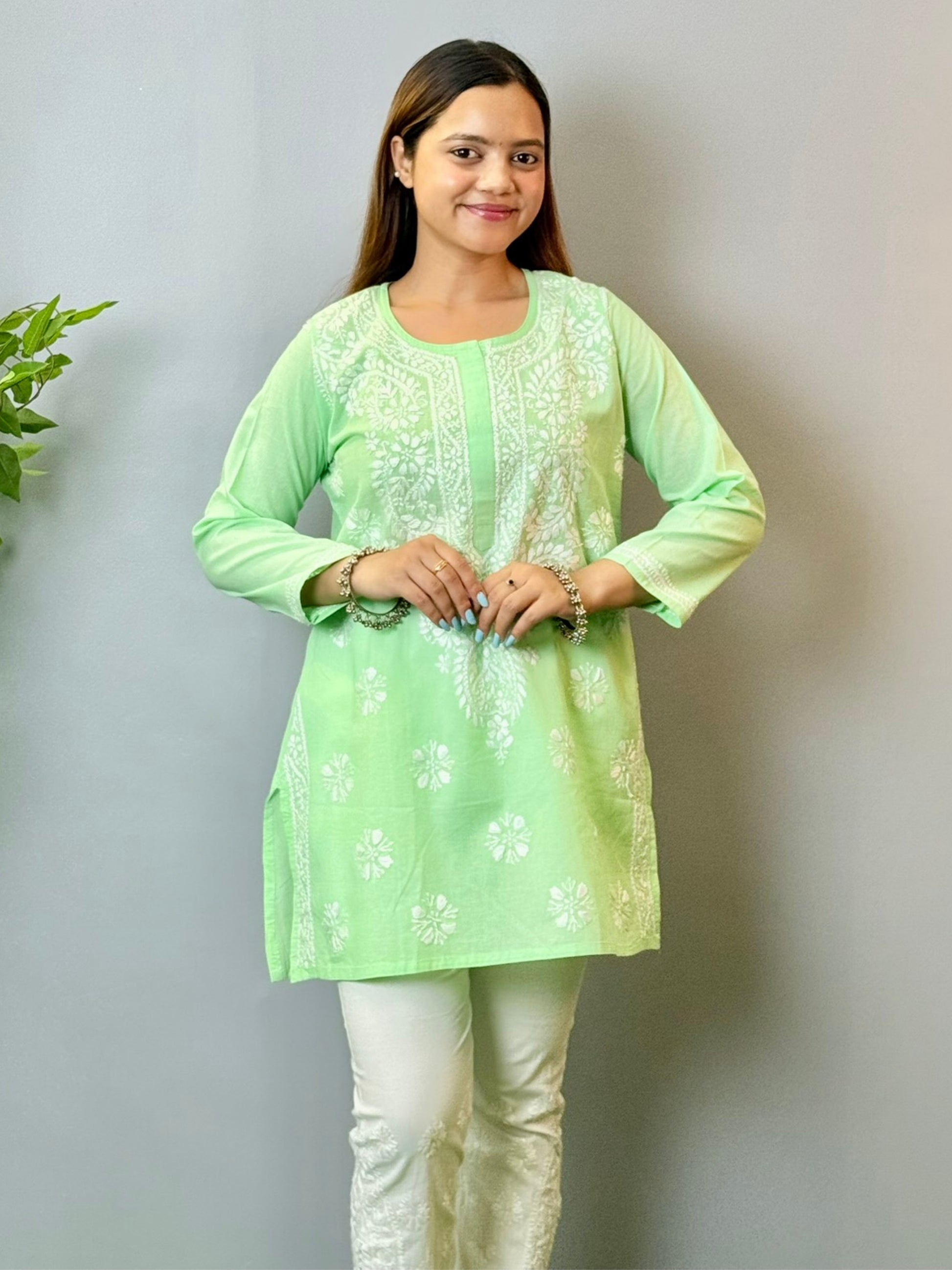 Model wearing a mint green cotton short Lucknowi chikankari kurta with white embroidery, paired with white straight pants.