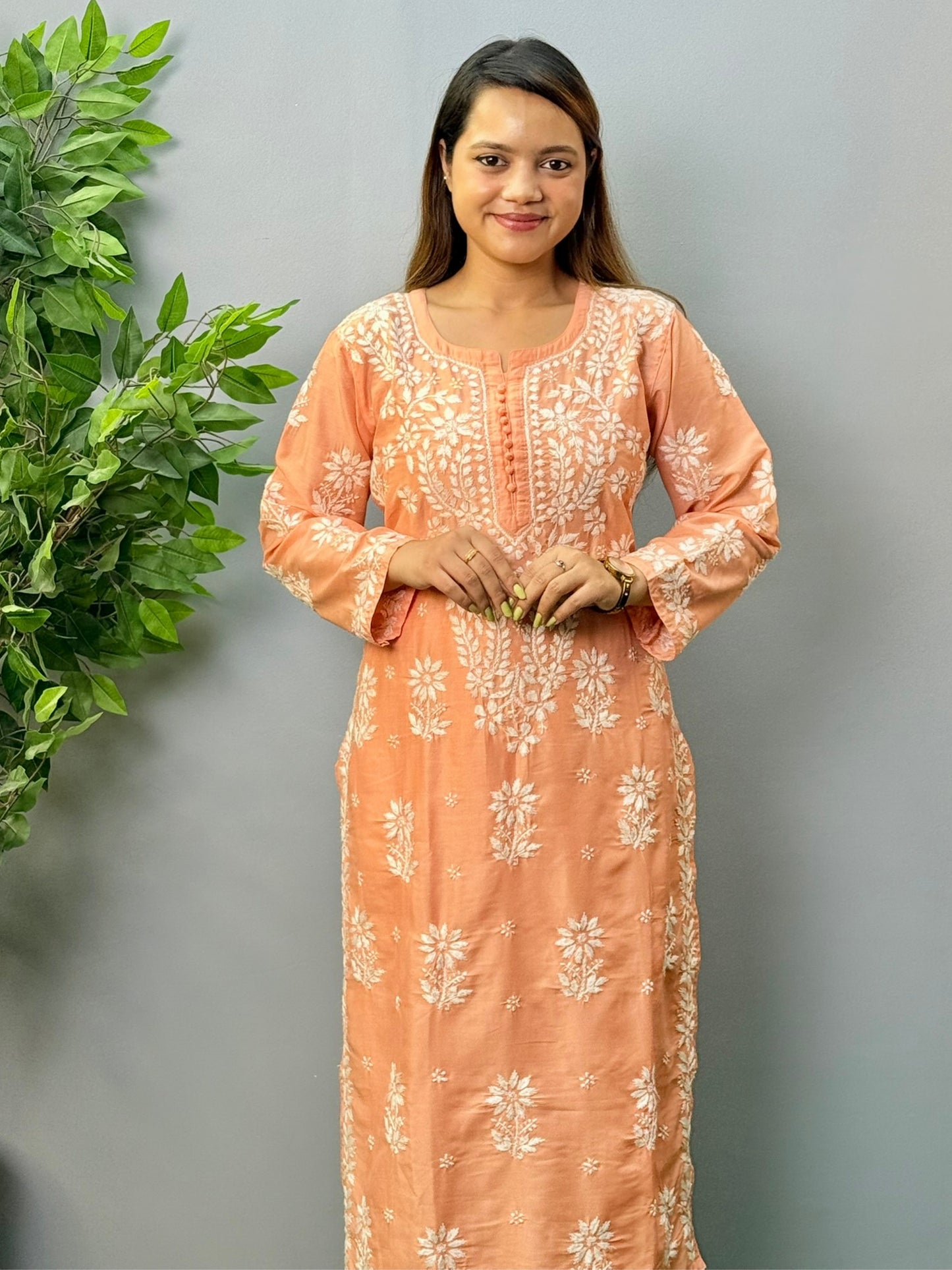 Model wearing a peach muslin chikankari kurta and pant set with white embroidery