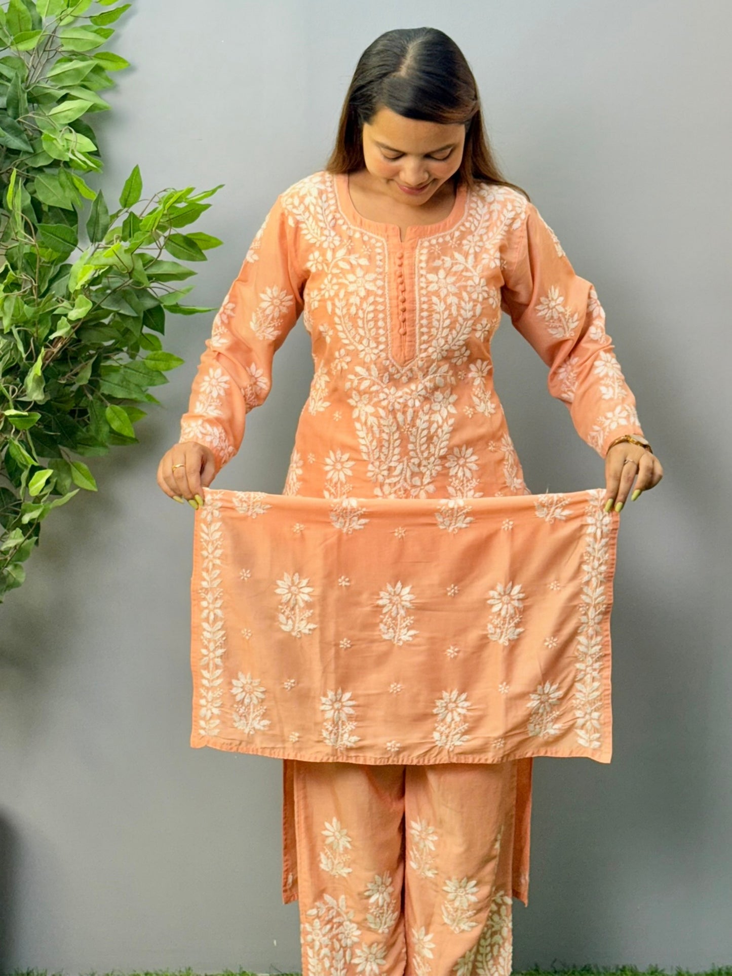 Model wearing a peach muslin chikankari kurta and pant set with white embroidery