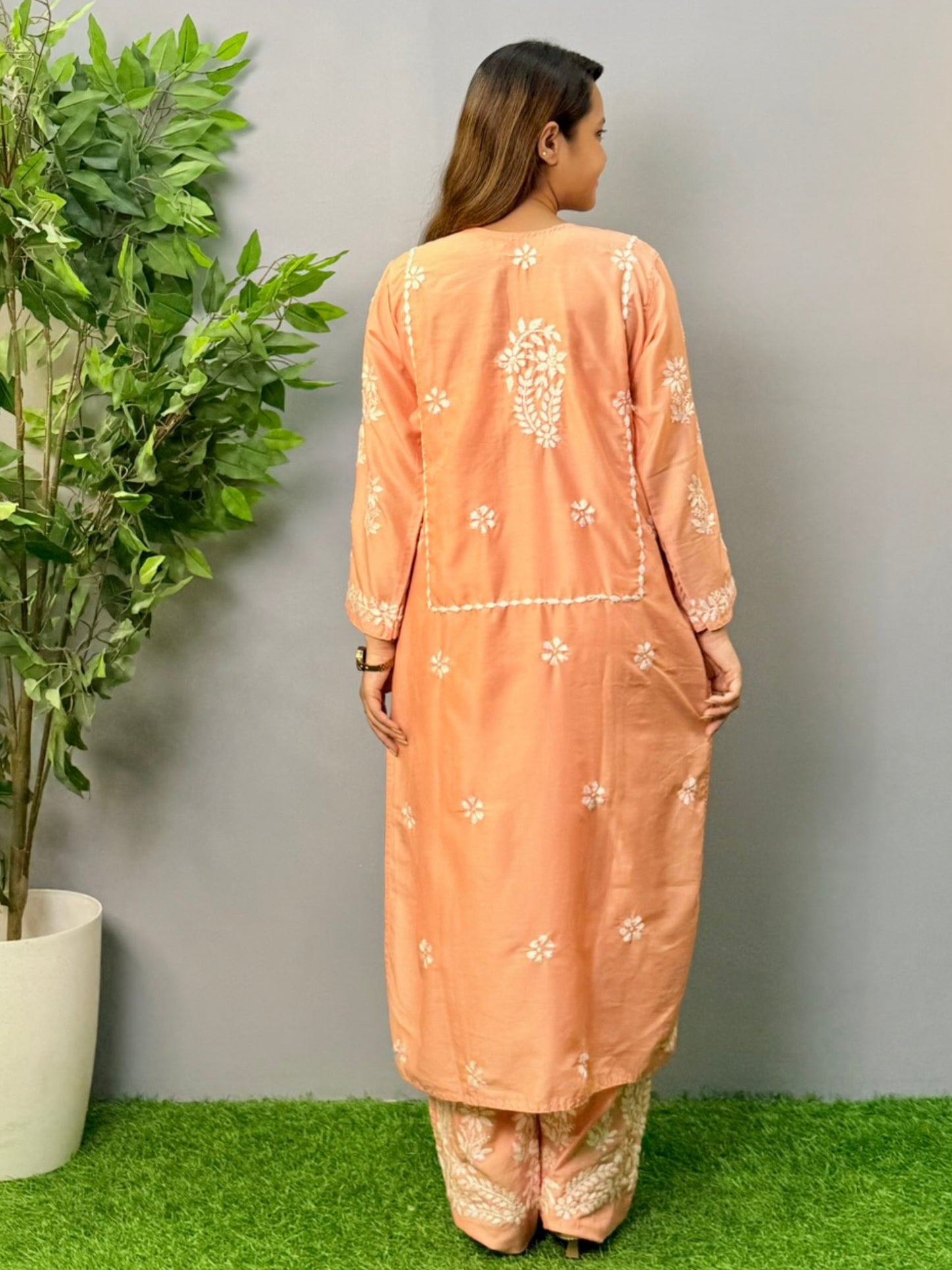 Model wearing a peach muslin chikankari kurta and pant set with white embroidery