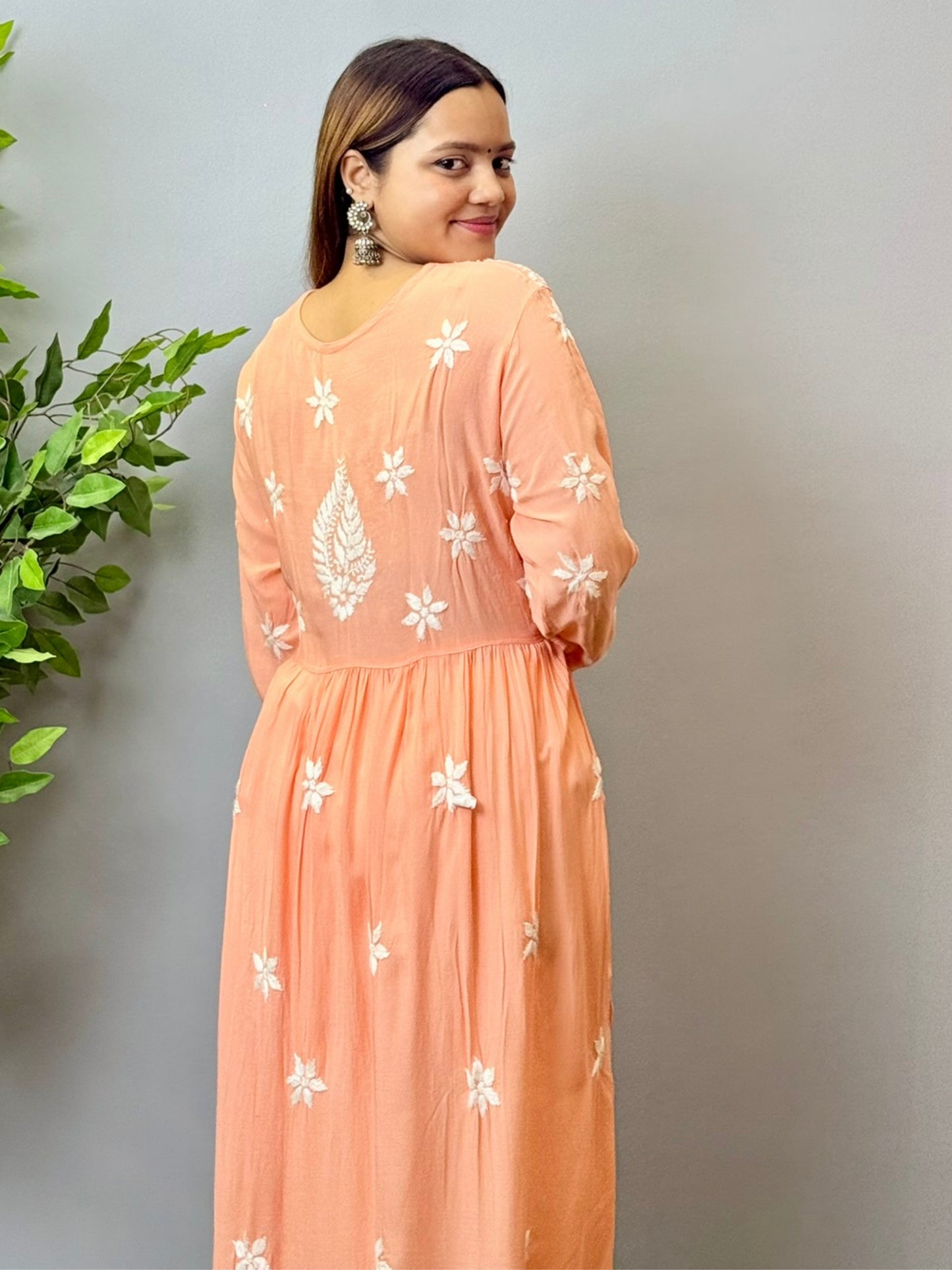 Model wearing a peach Lucknowi chikankari long frock in soft modal fabric with intricate white hand embroidery and a flared silhouette.