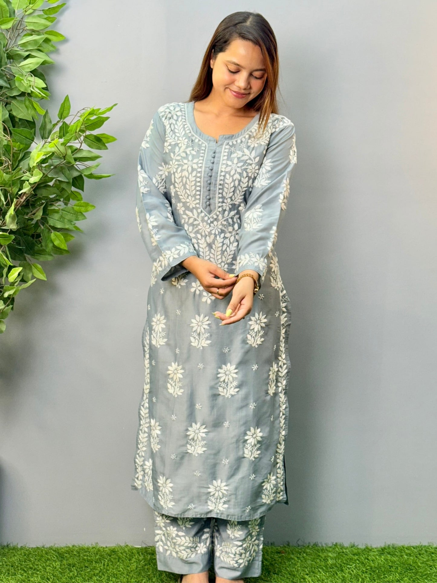 Model wearing a steel grey muslin chikankari kurta and pant set with intricate white embroidery