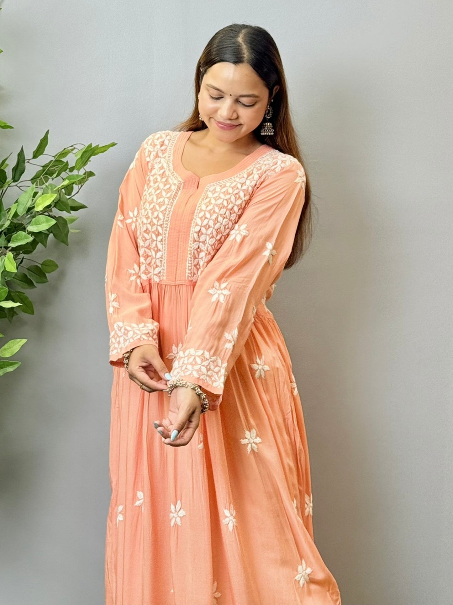 Model wearing a peach Lucknowi chikankari long frock in soft modal fabric with intricate white hand embroidery and a flared silhouette.