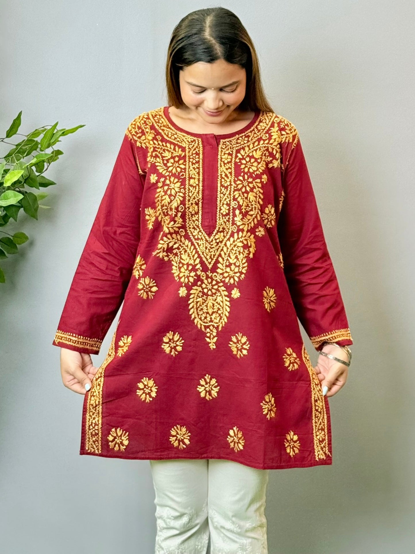 Model wearing a maroon short cotton Lucknowi chikankari kurta with mustard embroidery, styled with white pants.