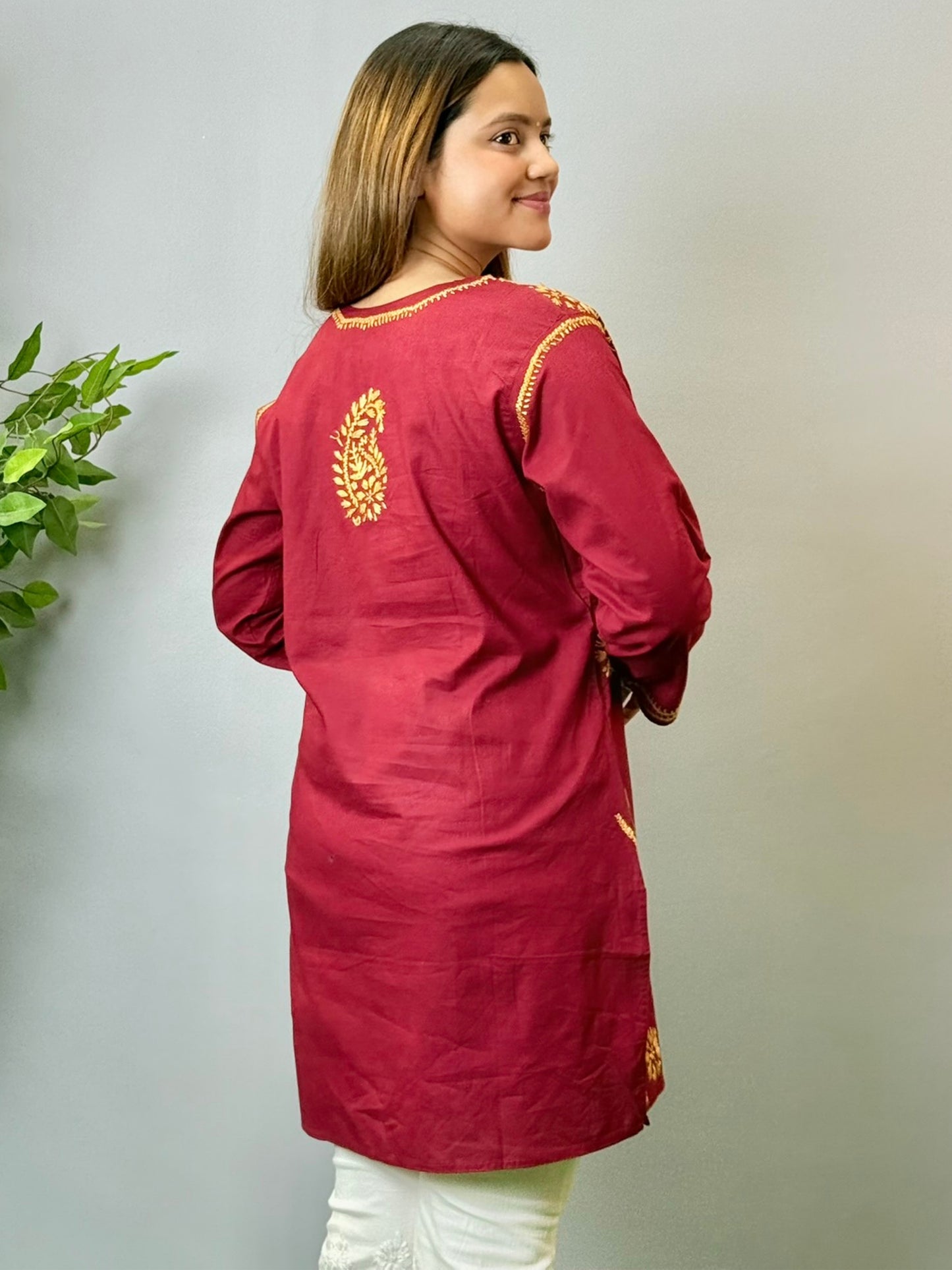 Model wearing a maroon short cotton Lucknowi chikankari kurta with mustard embroidery, styled with white pants.