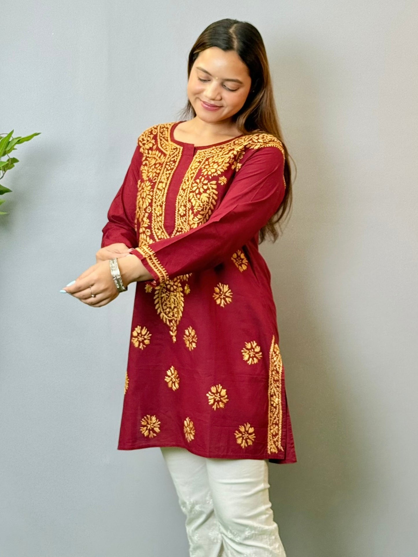 Model wearing a maroon short cotton Lucknowi chikankari kurta with mustard embroidery, styled with white pants.