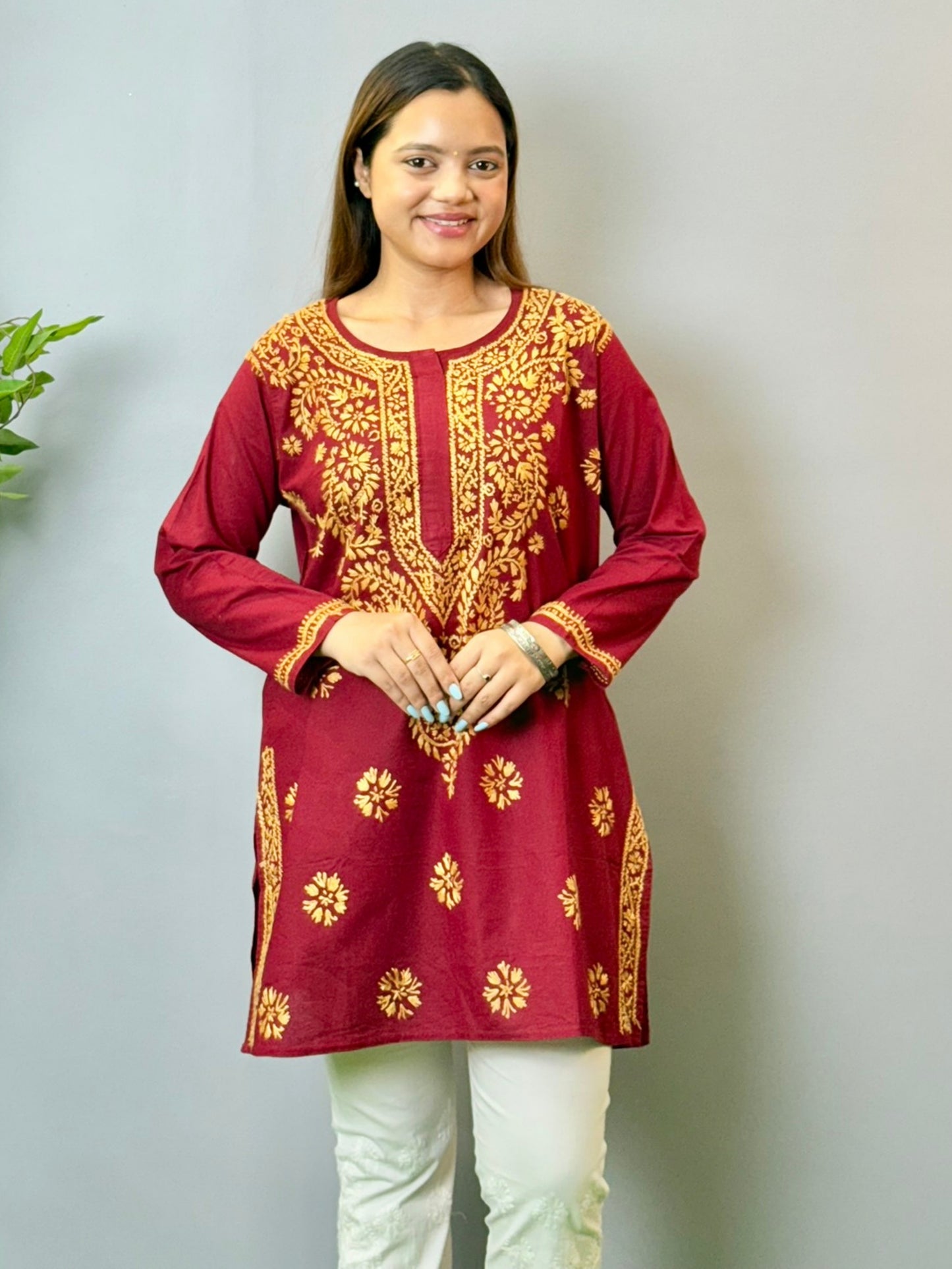 Model wearing a maroon short cotton Lucknowi chikankari kurta with mustard embroidery, styled with white pants.