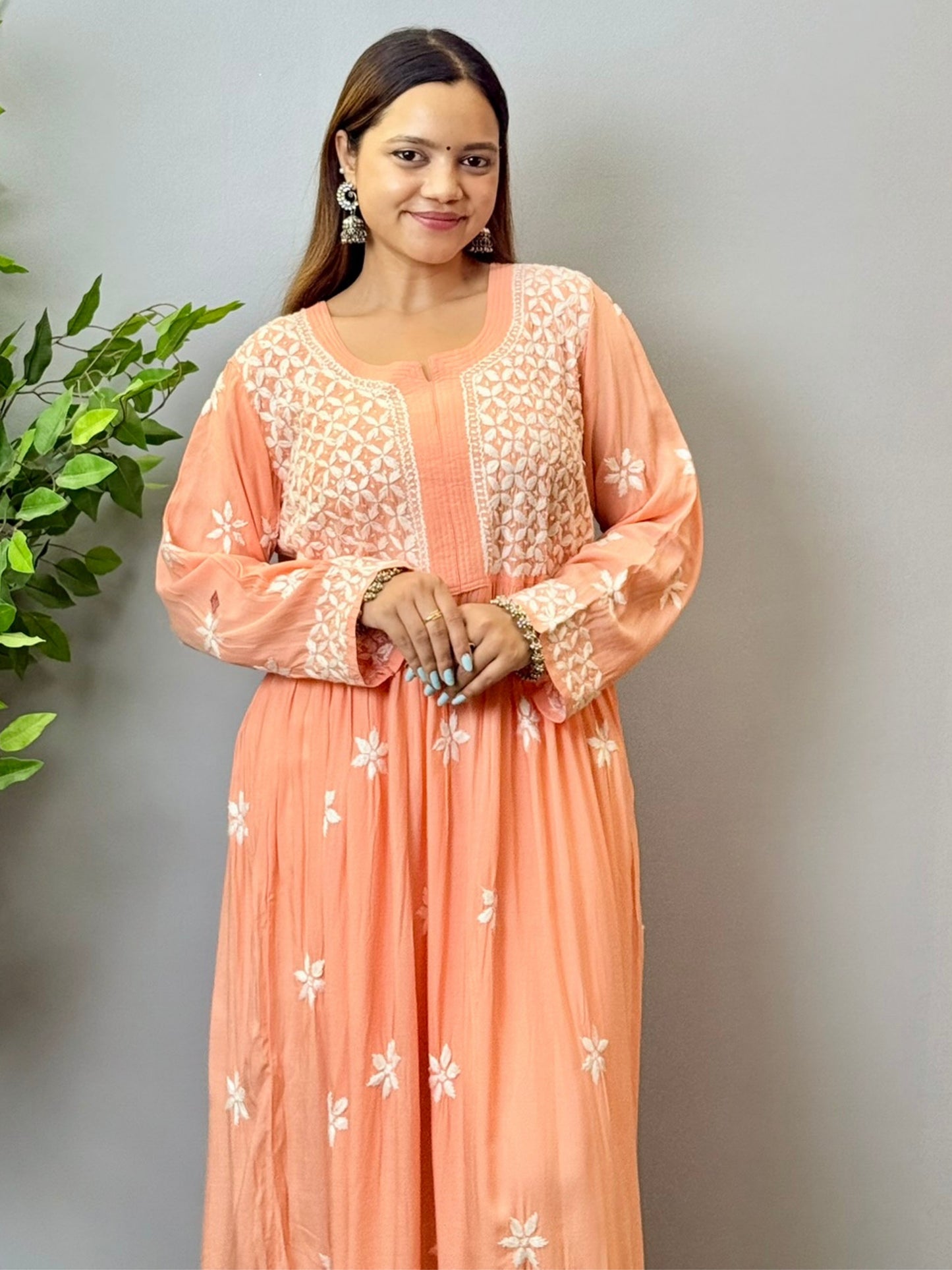 Model wearing a peach Lucknowi chikankari long frock in soft modal fabric with intricate white hand embroidery and a flared silhouette.