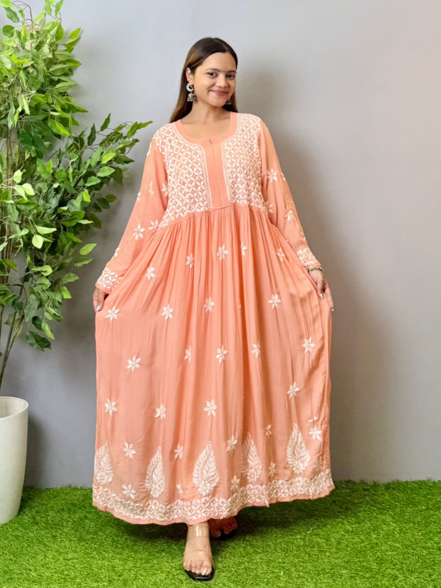 Model wearing a peach Lucknowi chikankari long frock in soft modal fabric with intricate white hand embroidery and a flared silhouette.