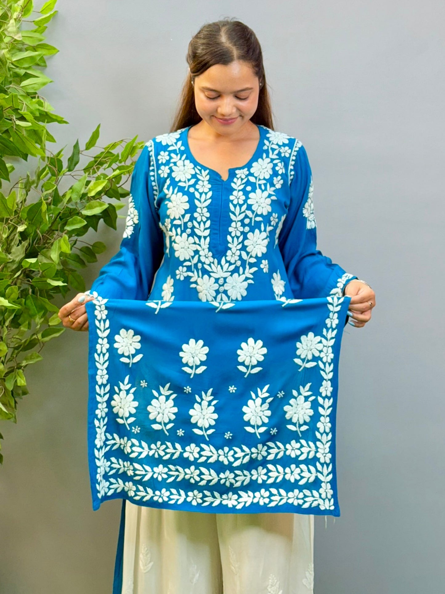 Woman wearing teal blue Chikankari kurta with white embroidery on modal fabric.