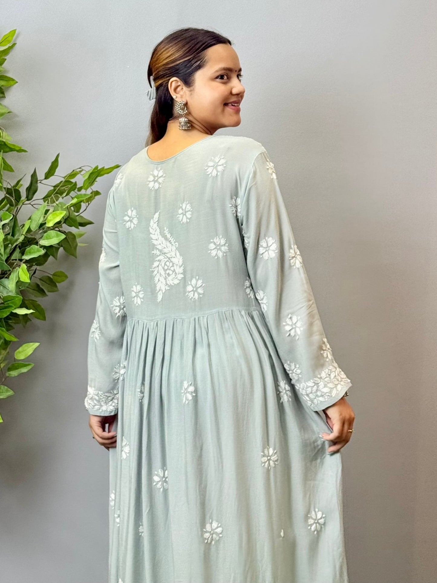 Model wearing a dusty grey Lucknowi chikankari long frock in modal fabric with intricate white hand embroidery and soft flared styling.