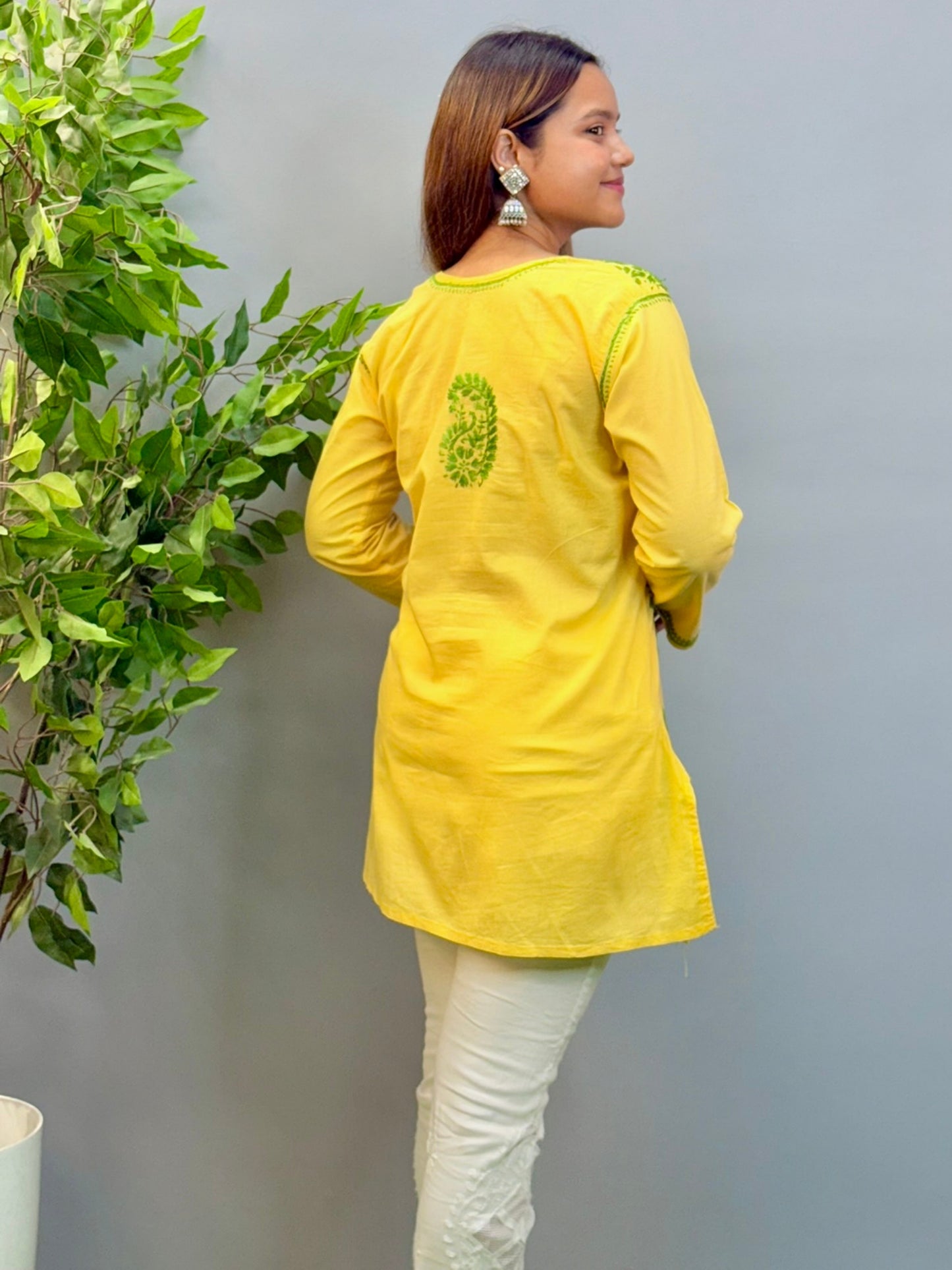 Model wearing bright yellow short cotton chikankari kurta with green contrast embroidery.