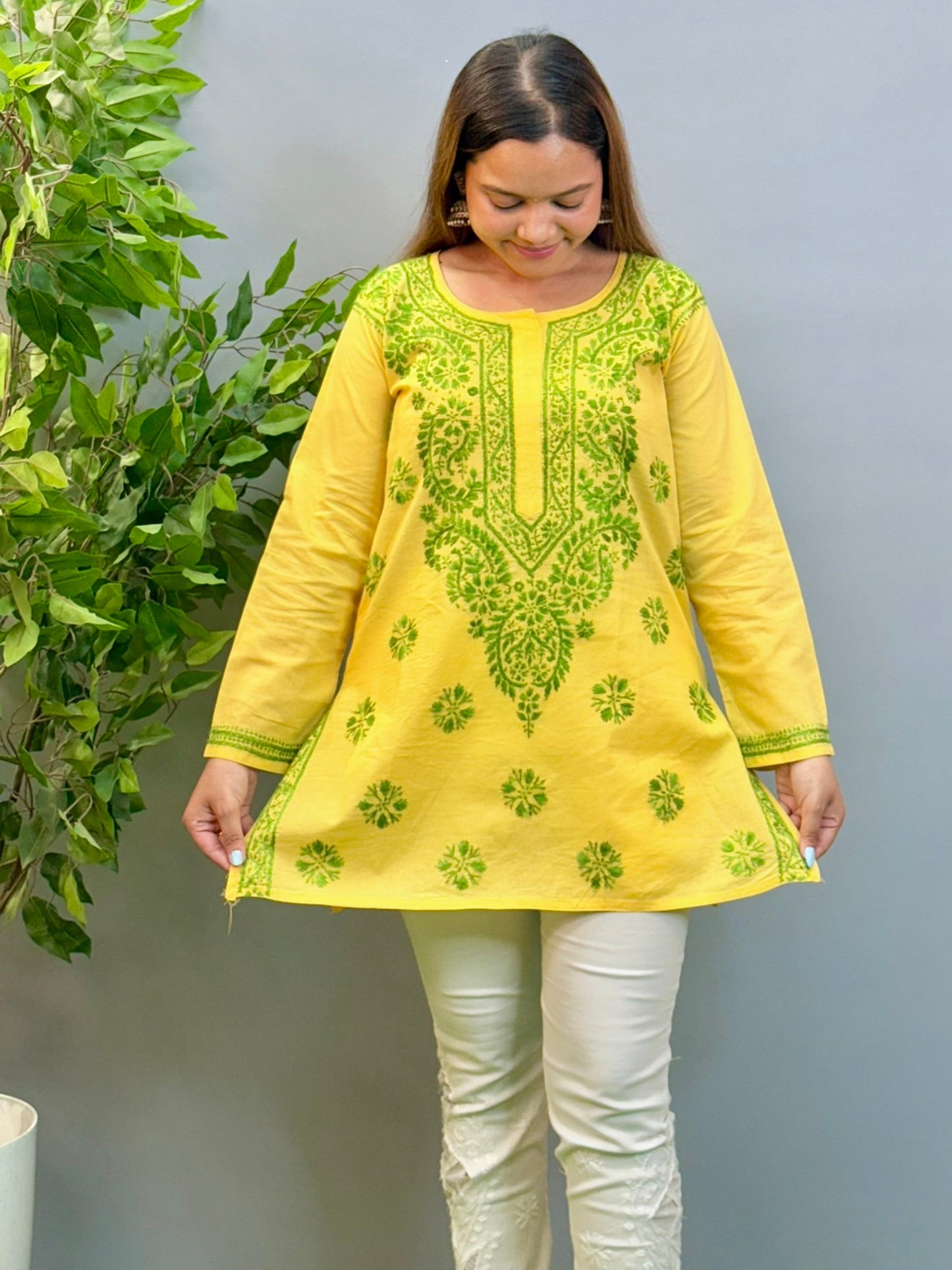 Model wearing bright yellow short cotton chikankari kurta with green contrast embroidery.