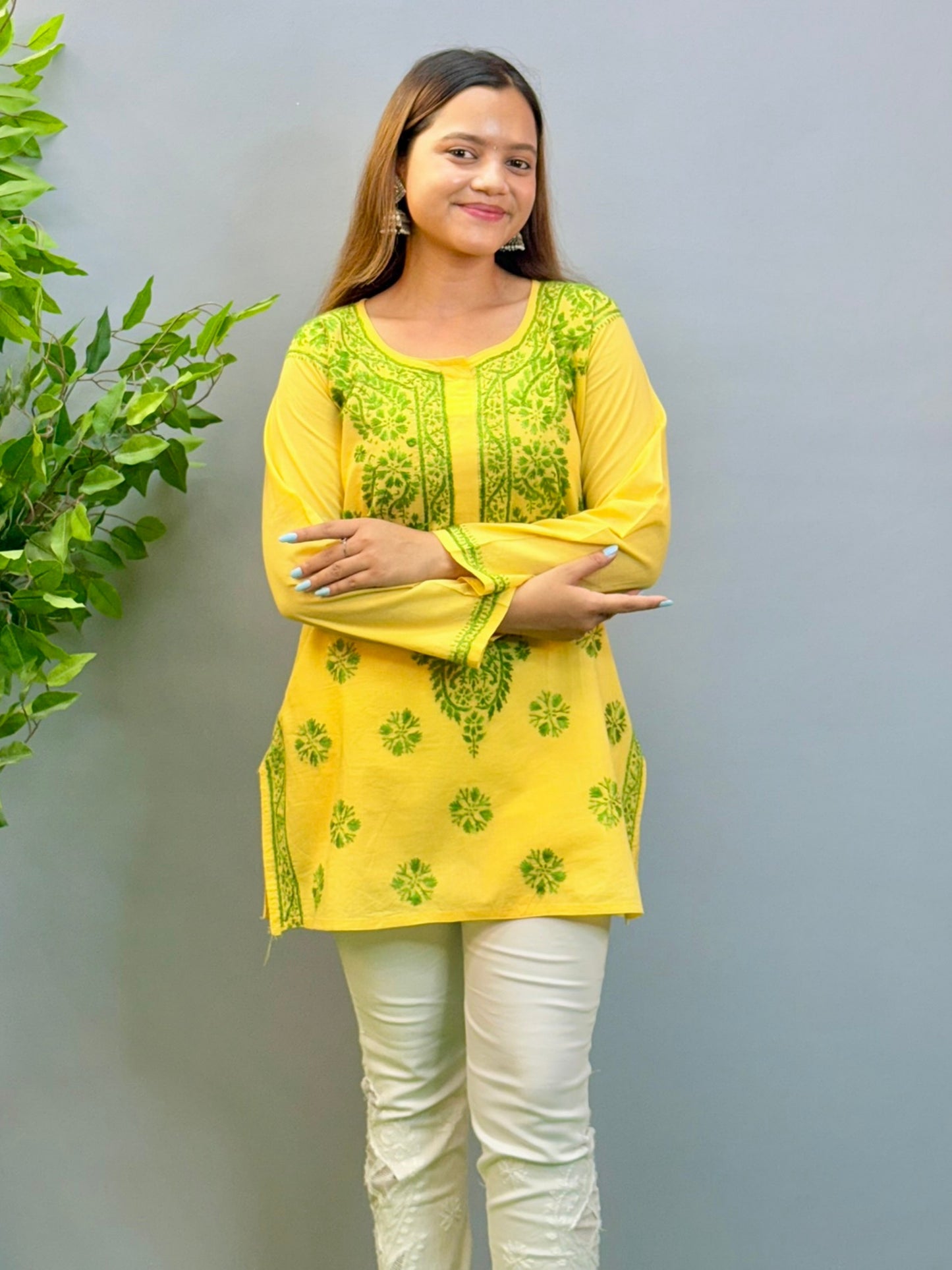 Model wearing bright yellow short cotton chikankari kurta with green contrast embroidery.