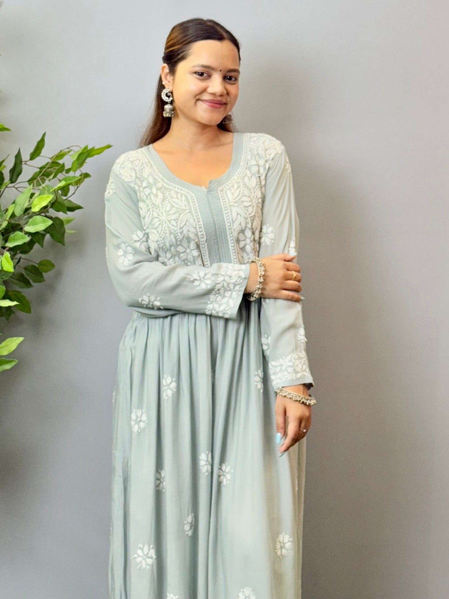 Model wearing a dusty grey Lucknowi chikankari long frock in modal fabric with intricate white hand embroidery and soft flared styling.