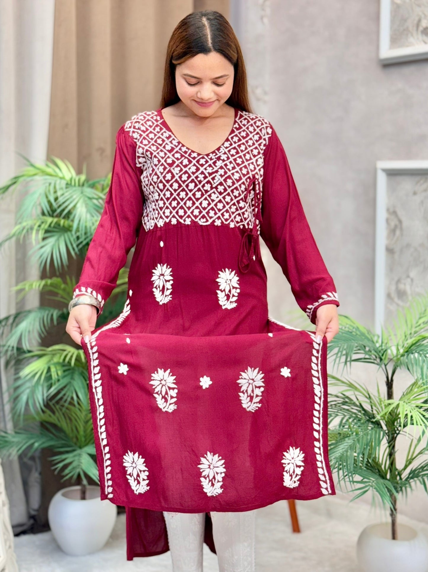 Model wearing a maroon Lucknowi chikankari angrakha-style kurta with white floral embroidery, in premium modal fabric.