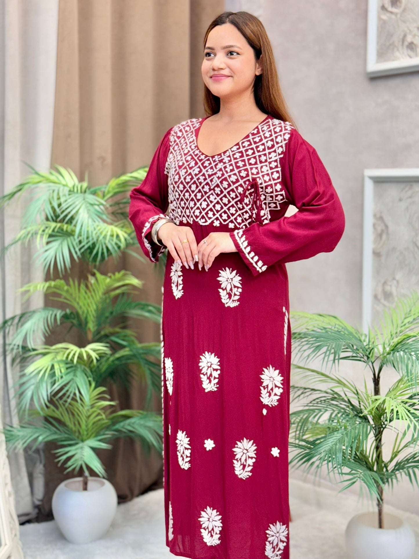 Model wearing a maroon Lucknowi chikankari angrakha-style kurta with white floral embroidery, in premium modal fabric.