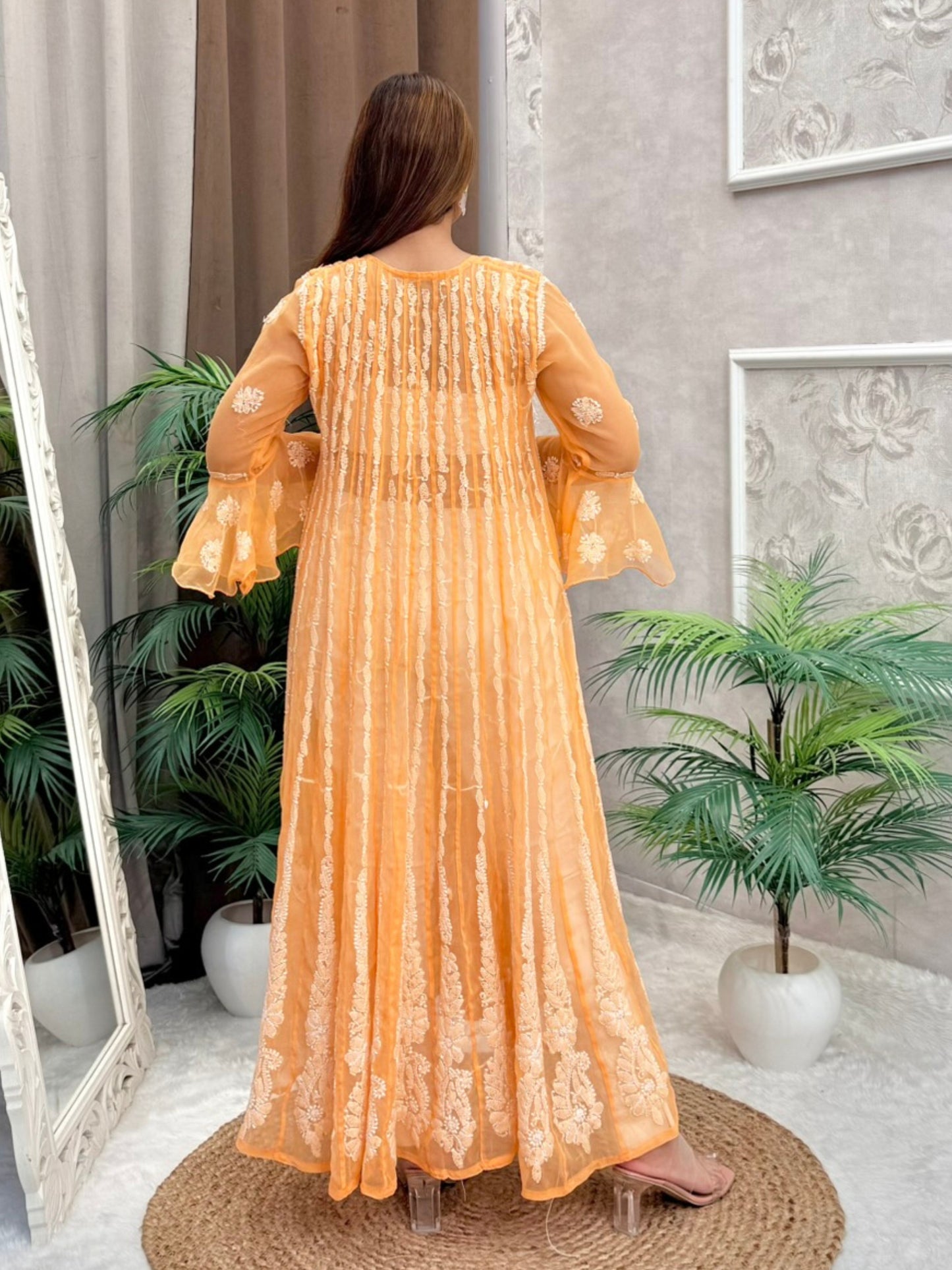 Model wearing a mustard sheer georgette Lucknowi chikankari long frock with heavy flare and fine embroidery, styled for a festive occasion.