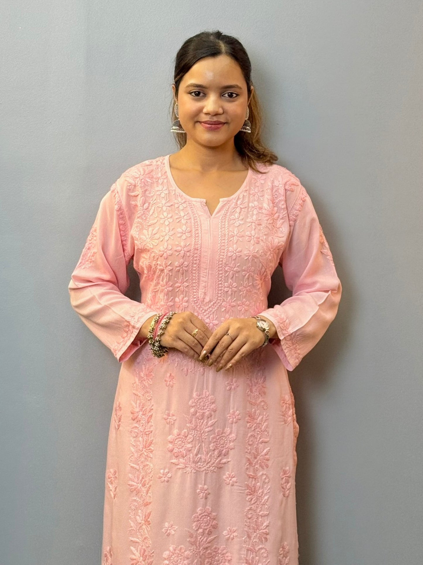 Woman wearing a blush pink modal chikankari kurta with intricate embroidery, paired with white palazzo pants