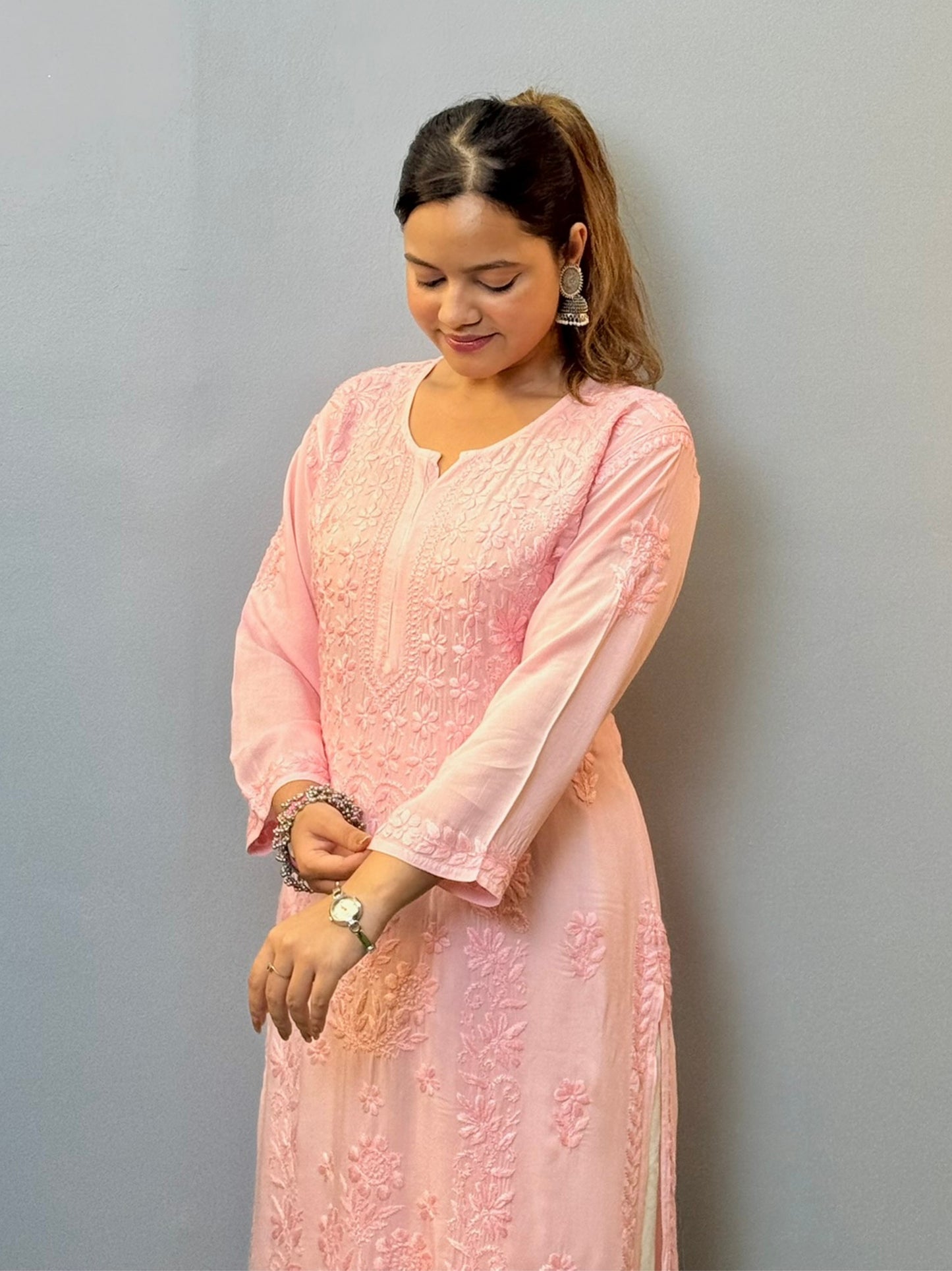 Woman wearing a blush pink modal chikankari kurta with intricate embroidery, paired with white palazzo pants