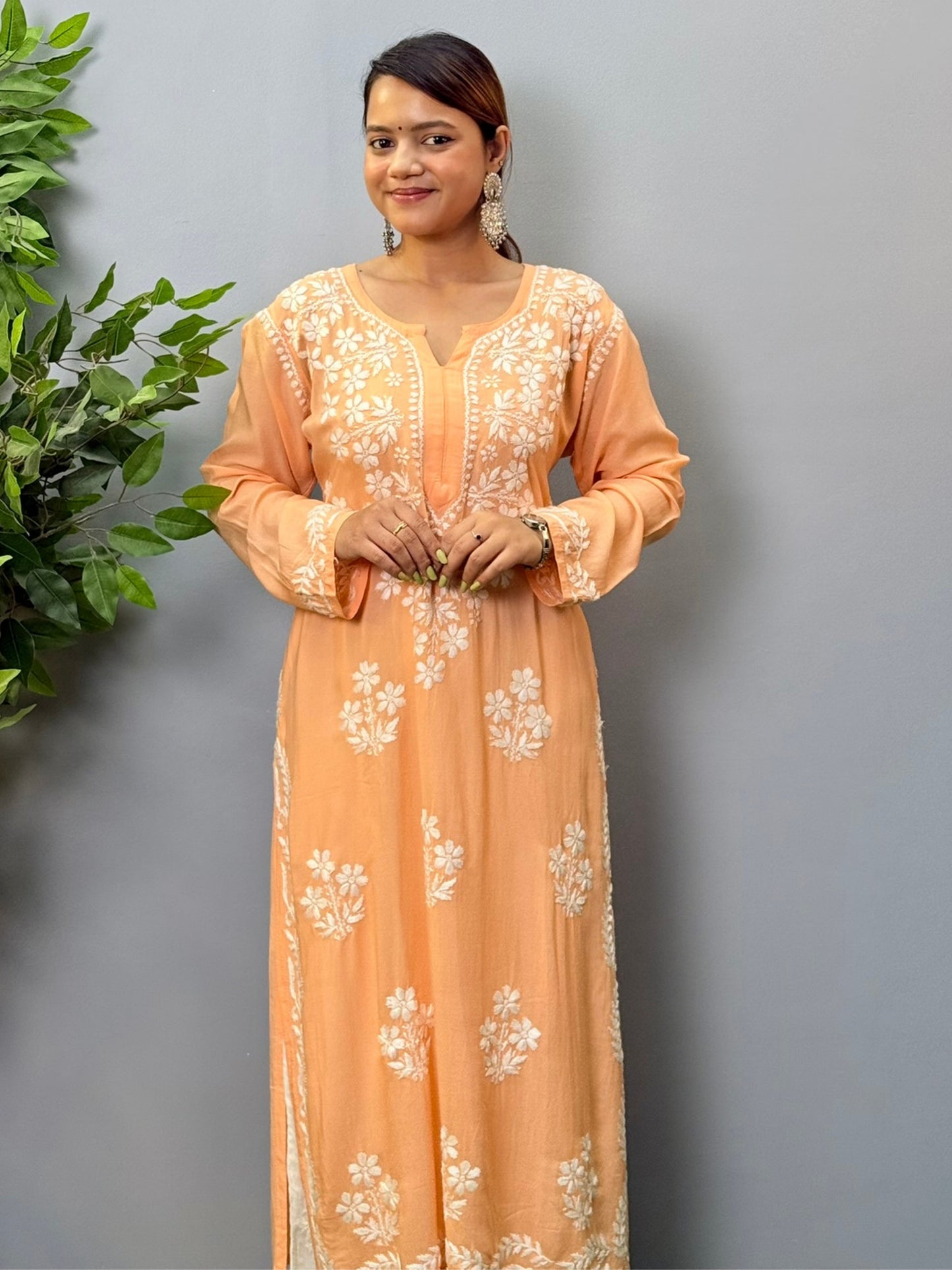 Model wearing a peach orange modal chikankari kurta with detailed white floral hand embroidery
