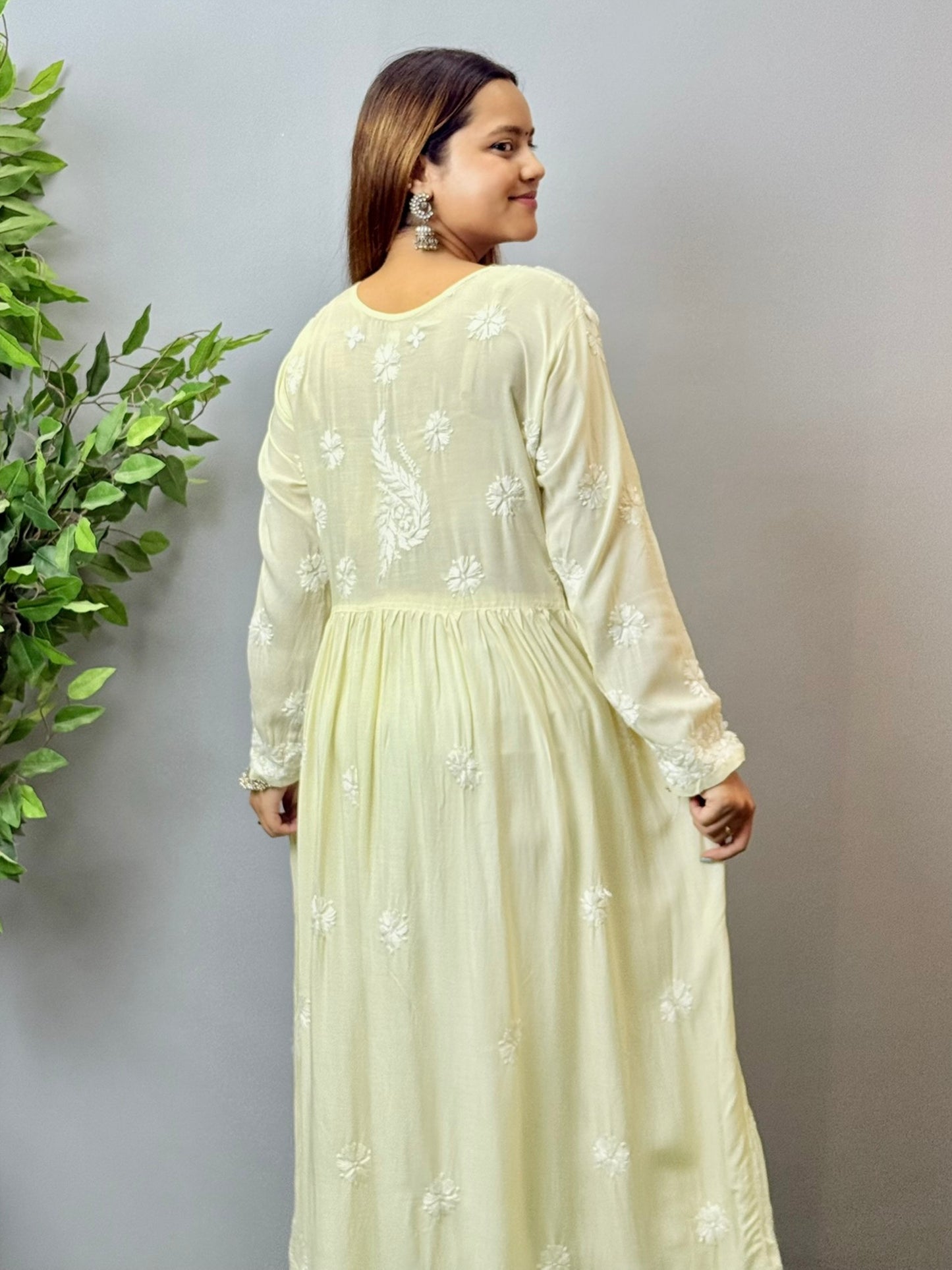 Model wearing an ivory cream Lucknowi chikankari long frock in modal fabric with white hand embroidery and soft flowy drape.