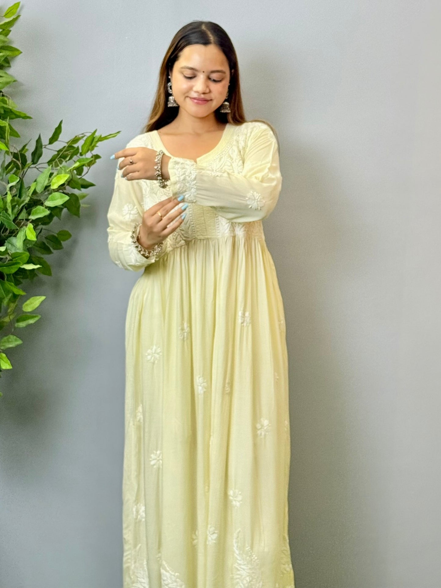 Model wearing an ivory cream Lucknowi chikankari long frock in modal fabric with white hand embroidery and soft flowy drape.