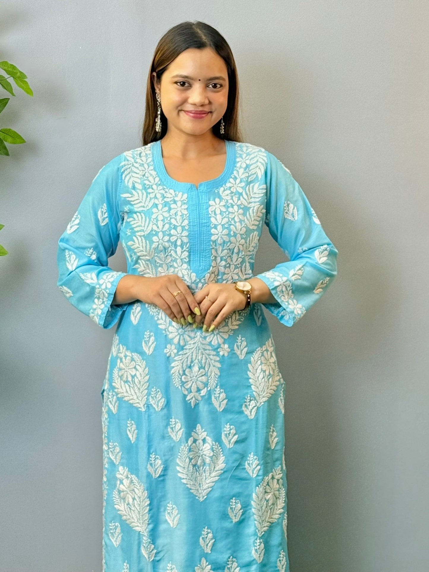 Woman wearing sky blue muslin Chikankari kurta and pant set with intricate white embroidery