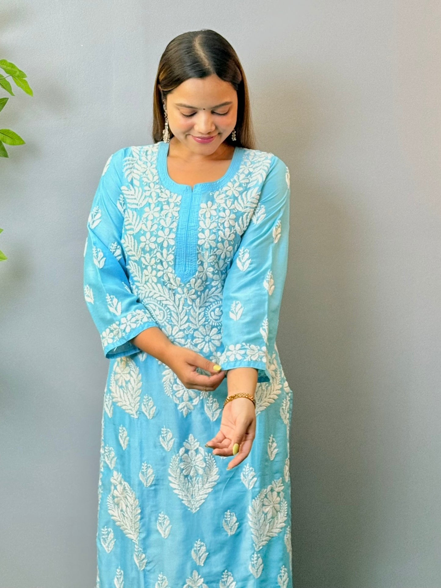 Woman wearing sky blue muslin Chikankari kurta and pant set with intricate white embroidery