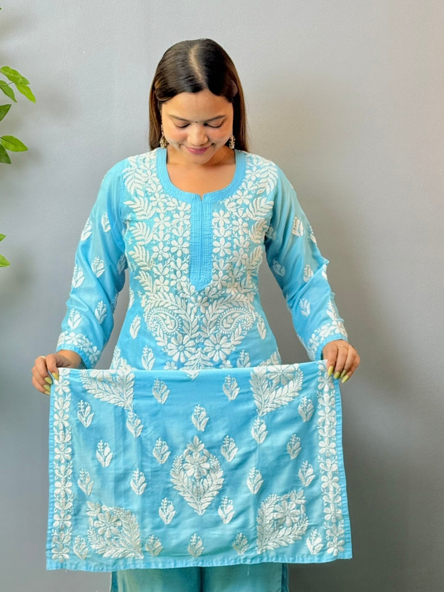 Woman wearing sky blue muslin Chikankari kurta and pant set with intricate white embroidery