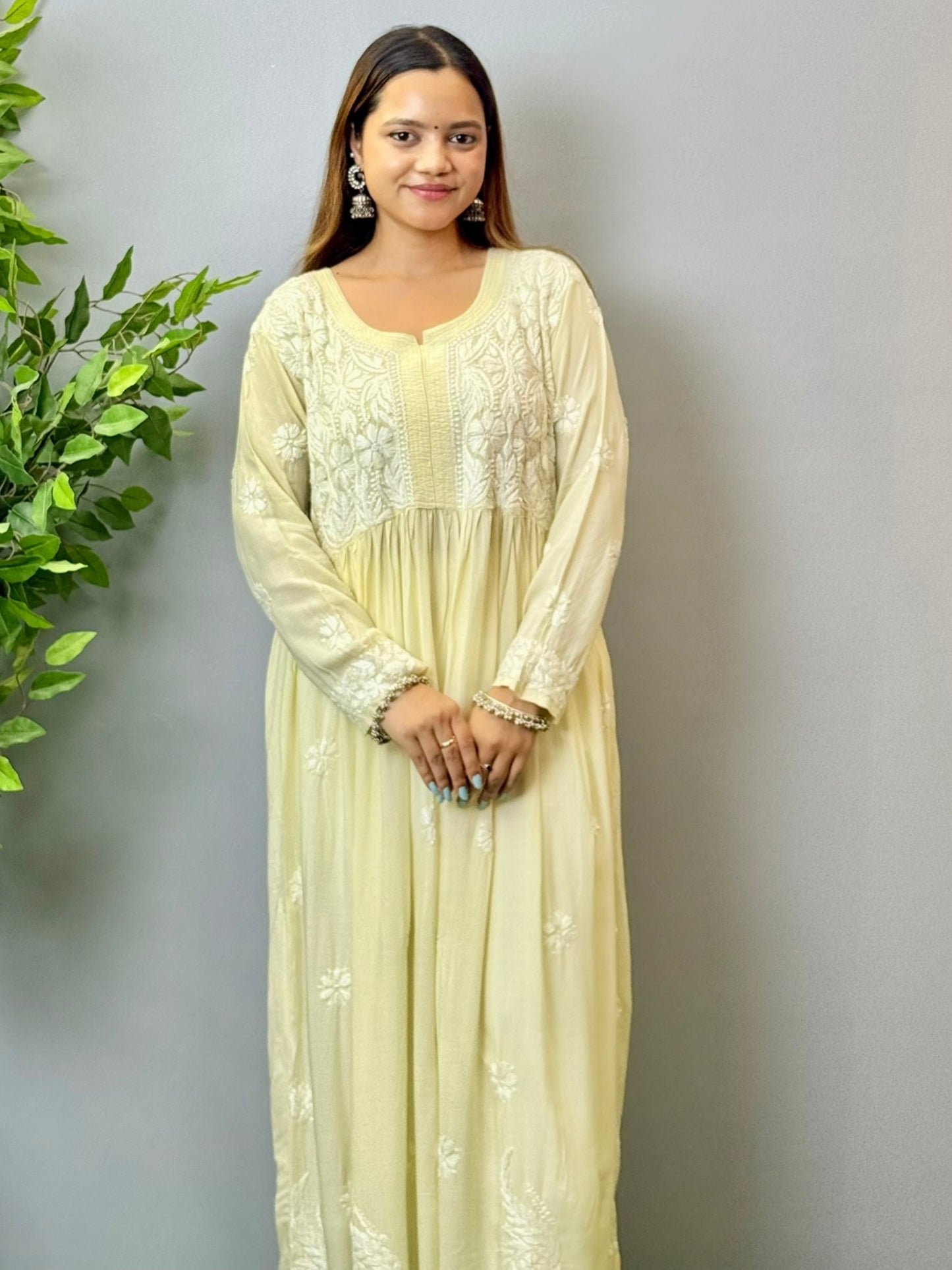 Model wearing an ivory cream Lucknowi chikankari long frock in modal fabric with white hand embroidery and soft flowy drape.