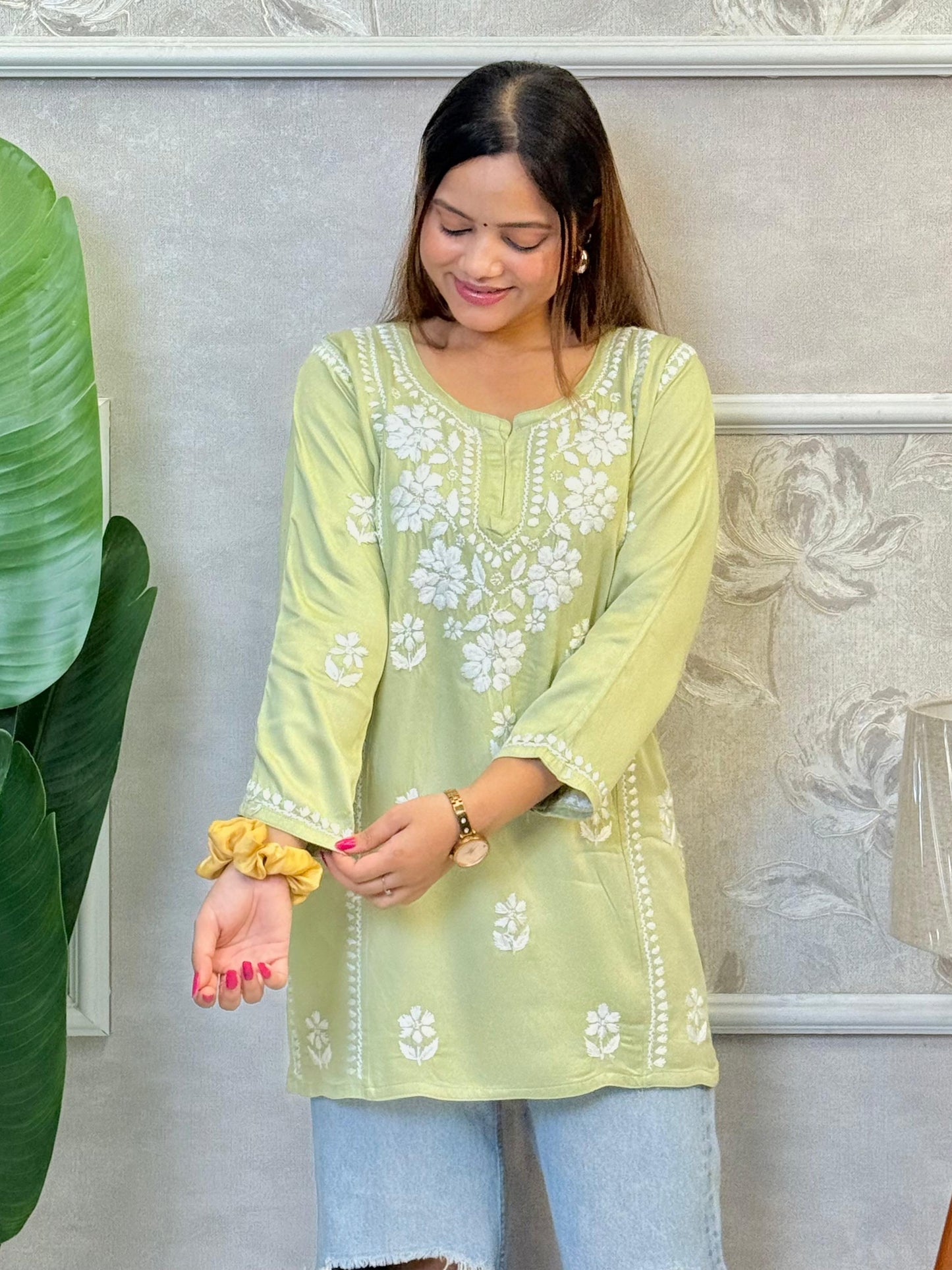 Light green satin short kurta with white Chikankari embroidery, worn with ripped jeans