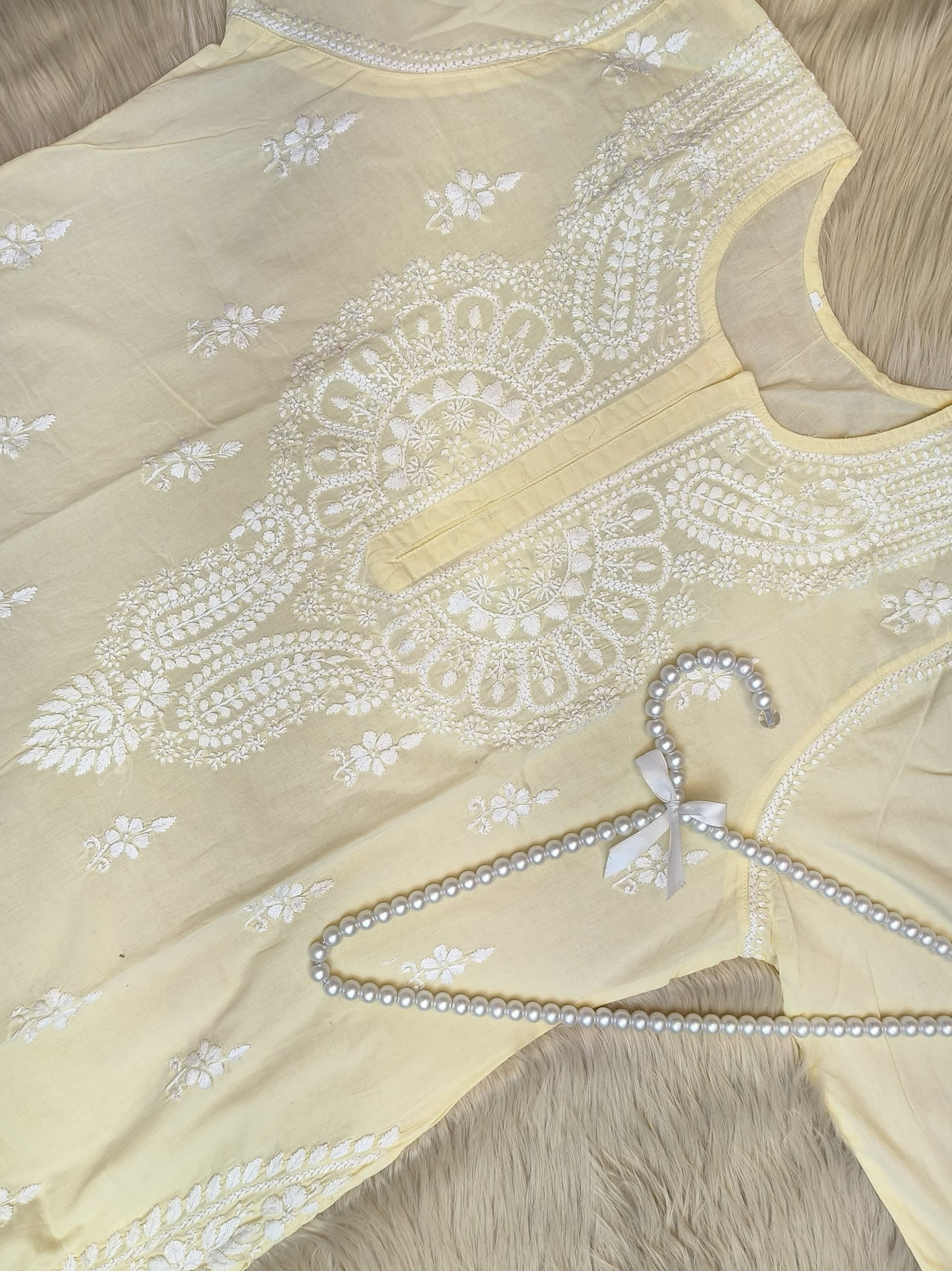 Pastel lemon cotton chikankari kurta with hand embroidery laid flat with pearl hanger