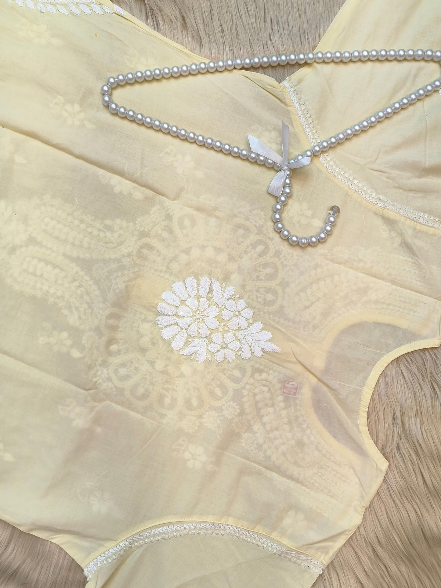 Pastel lemon cotton chikankari kurta with hand embroidery laid flat with pearl hanger