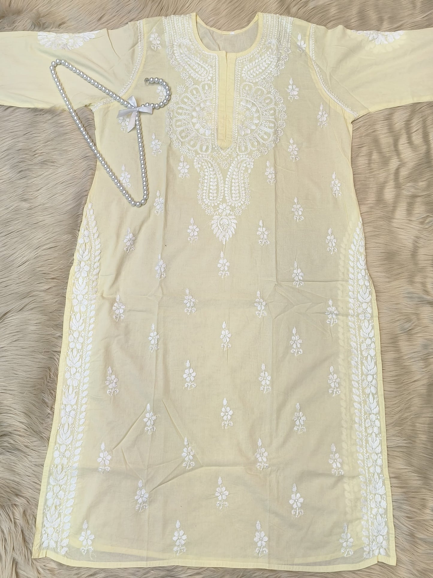 Pastel lemon cotton chikankari kurta with hand embroidery laid flat with pearl hanger