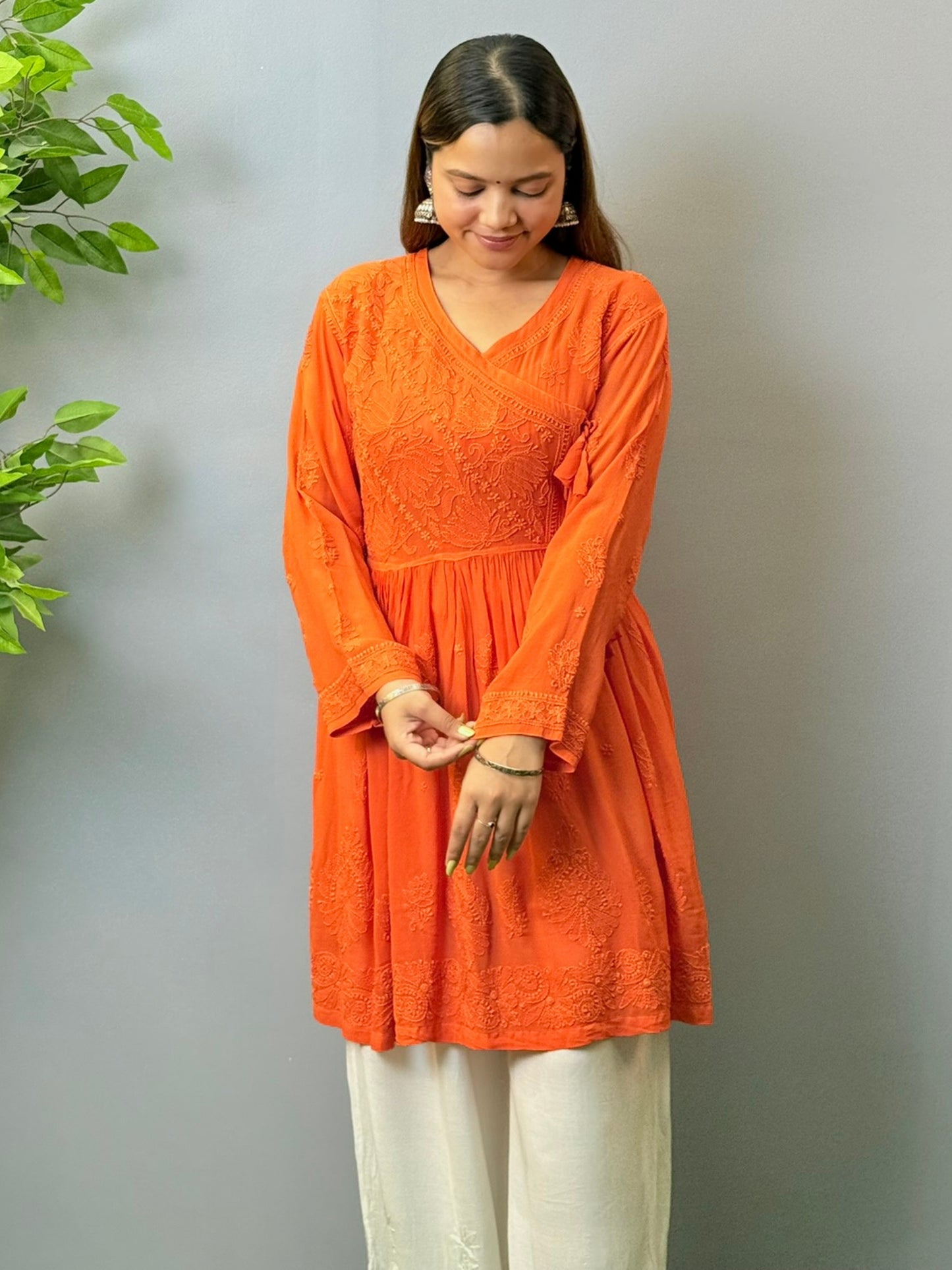 Woman wearing rust orange short chikankari angrakha kurta in viscose fabric