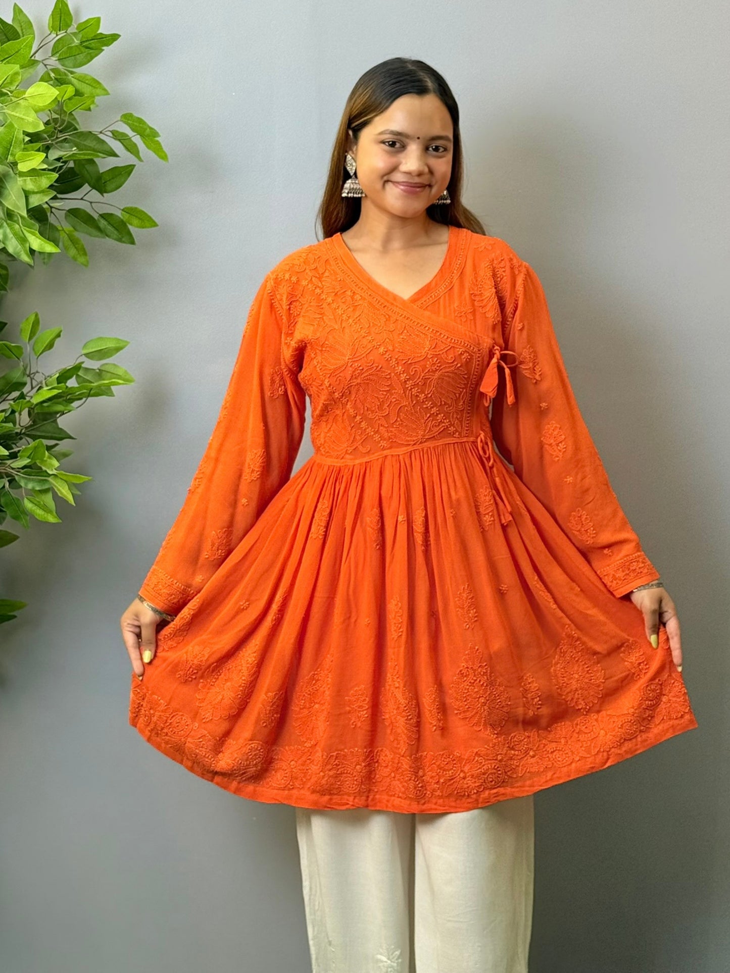 Woman wearing rust orange short chikankari angrakha kurta in viscose fabric