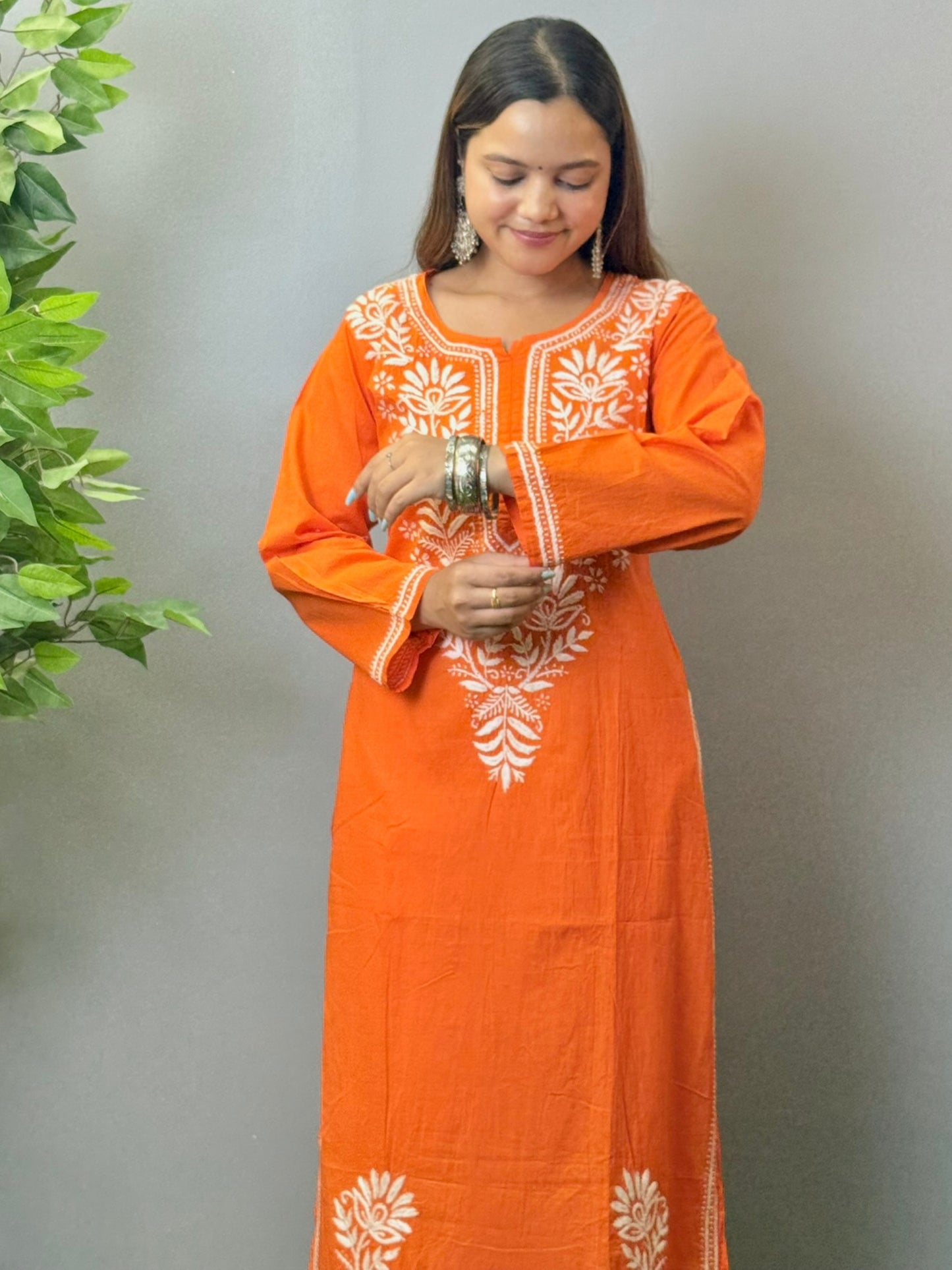 Model wearing a sunset orange cotton kurta with white hand chikankari embroidery.