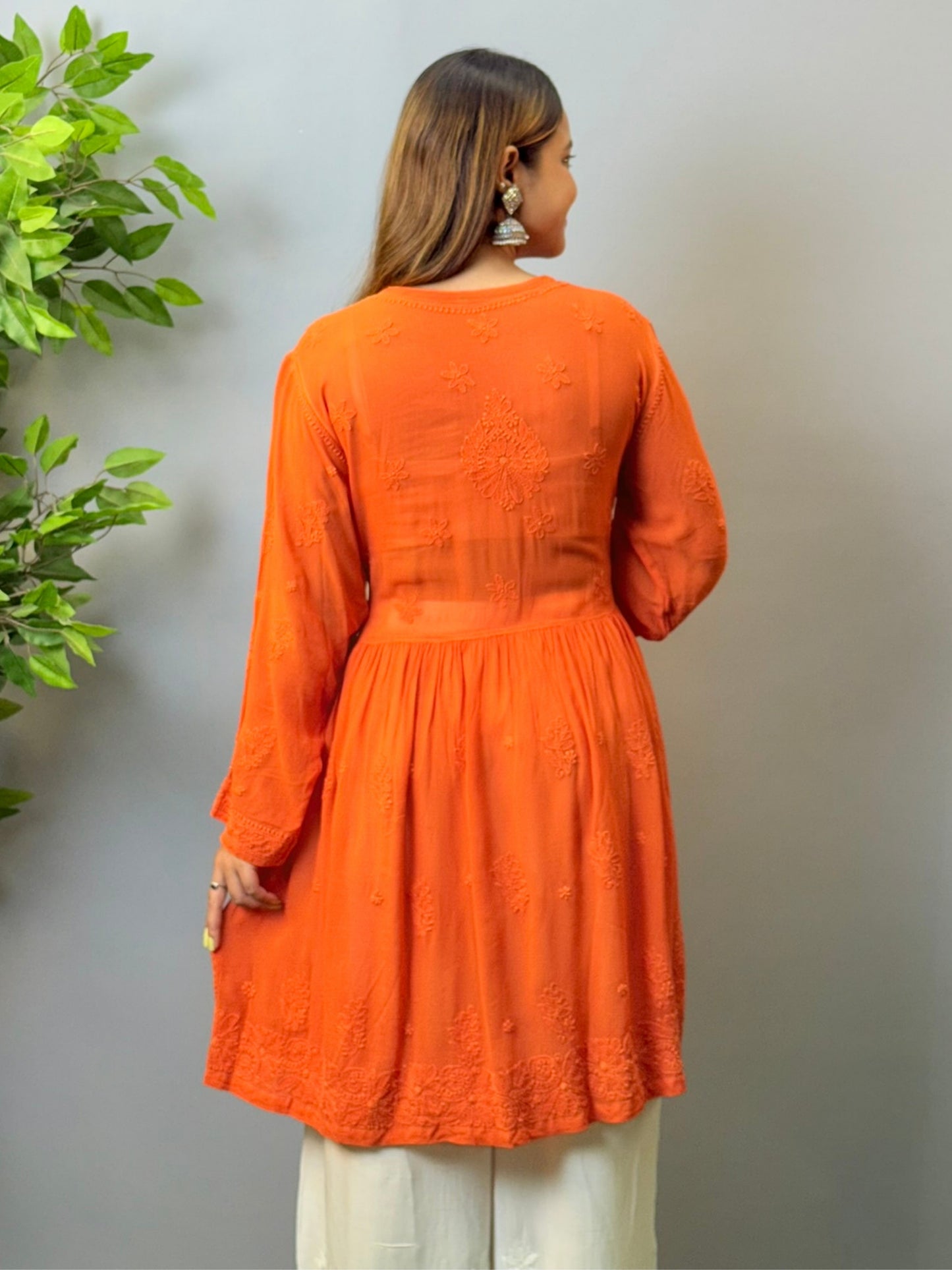 Woman wearing rust orange short chikankari angrakha kurta in viscose fabric