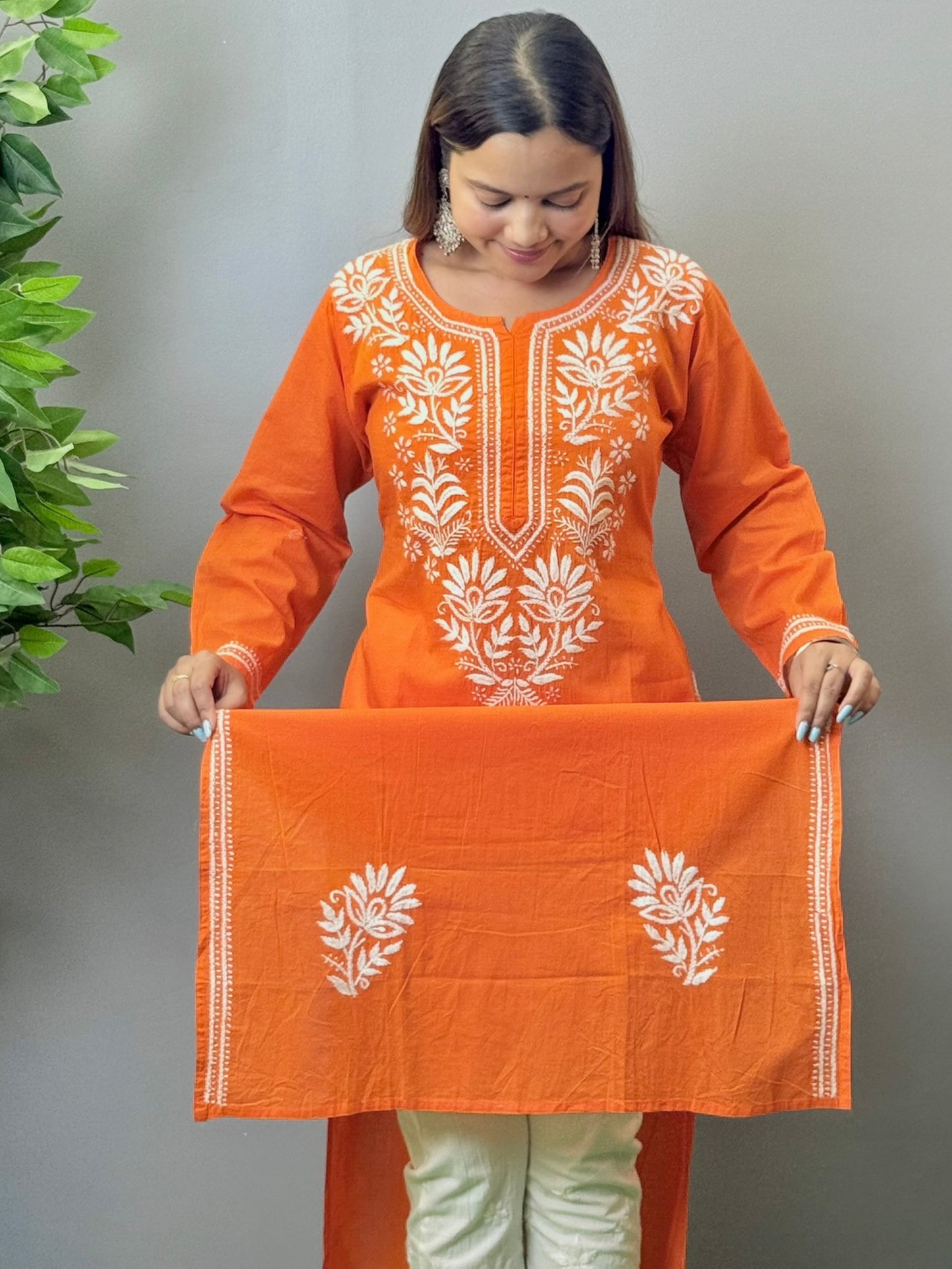 Model wearing a sunset orange cotton kurta with white hand chikankari embroidery.