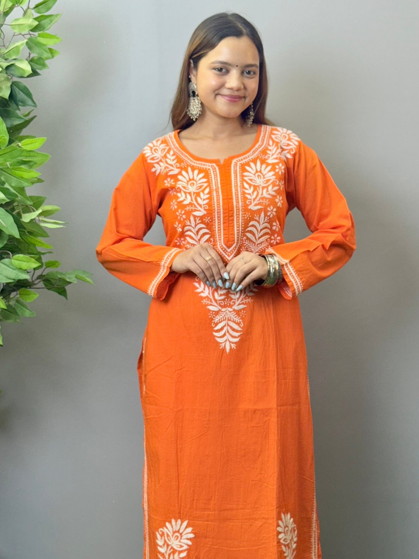 Model wearing a sunset orange cotton kurta with white hand chikankari embroidery.