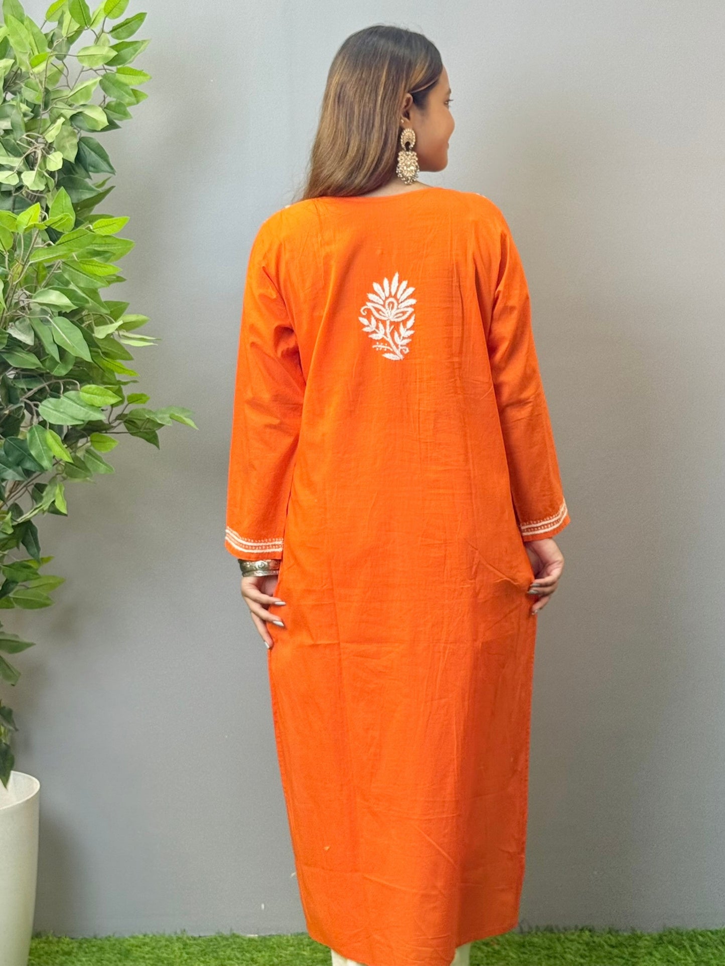 Model wearing a sunset orange cotton kurta with white hand chikankari embroidery.
