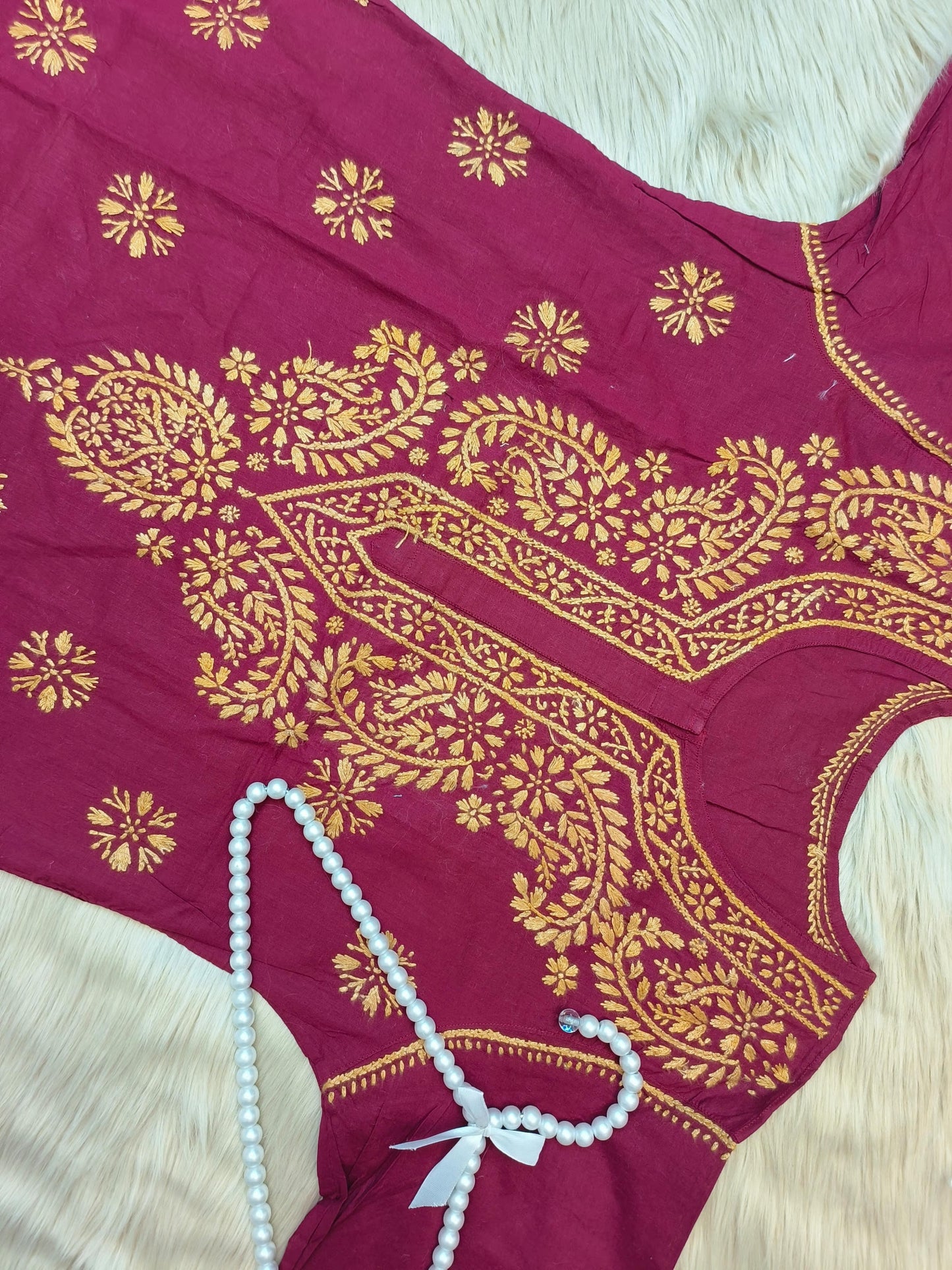 Maroon cotton short chikankari kurta with mustard hand embroidery laid flat on fur background