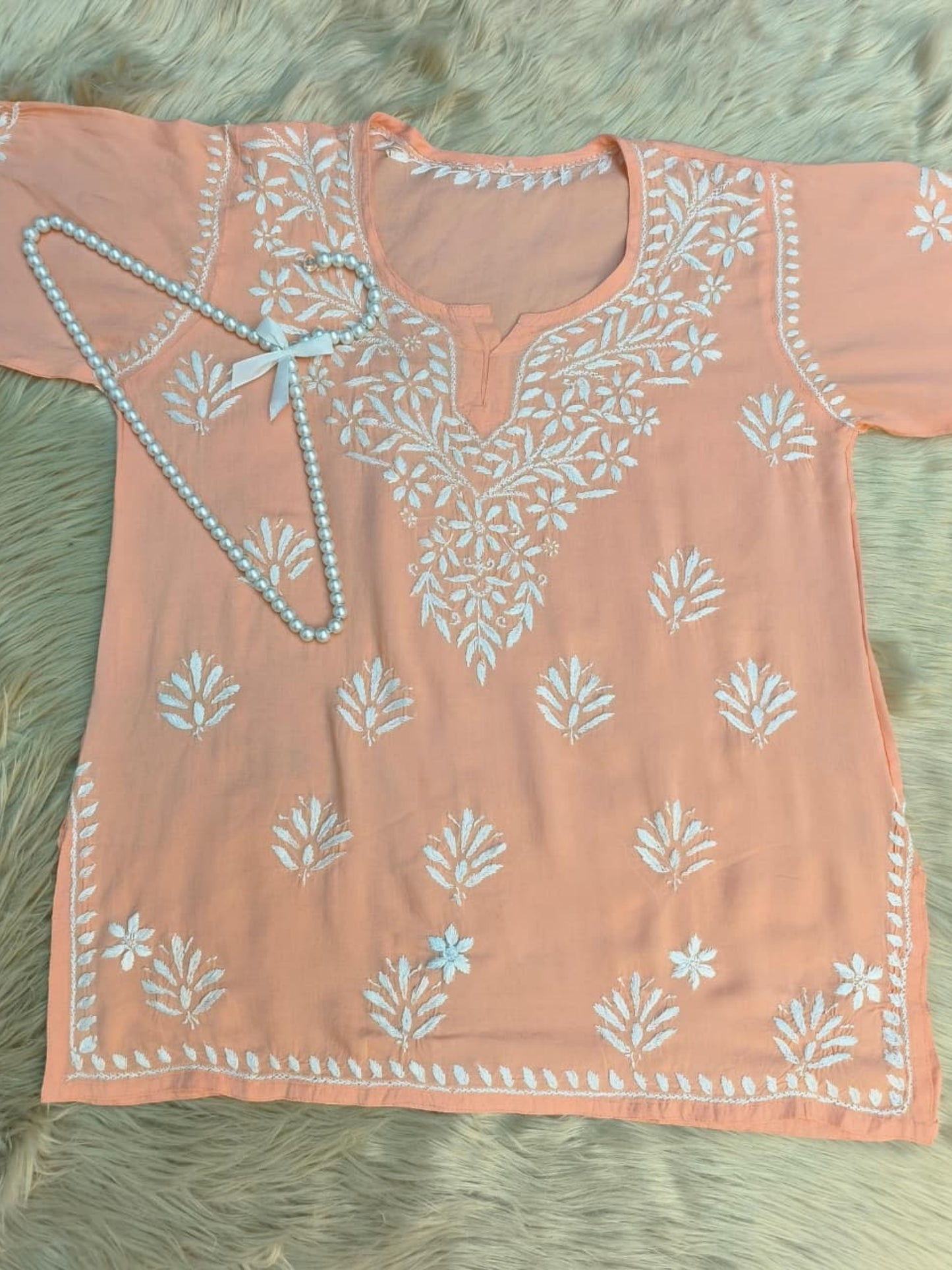 Peach modal short kurta with white hand-embroidered Lucknowi Chikankari design.