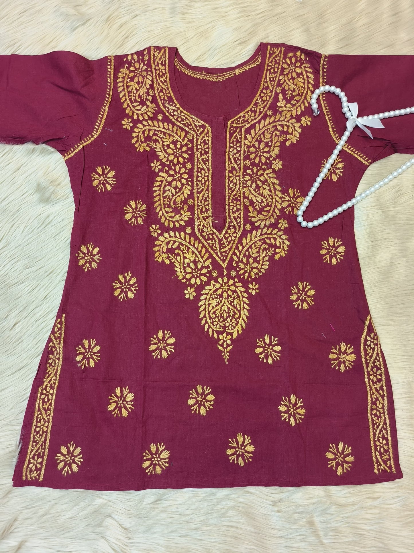 Maroon cotton short chikankari kurta with mustard hand embroidery laid flat on fur background